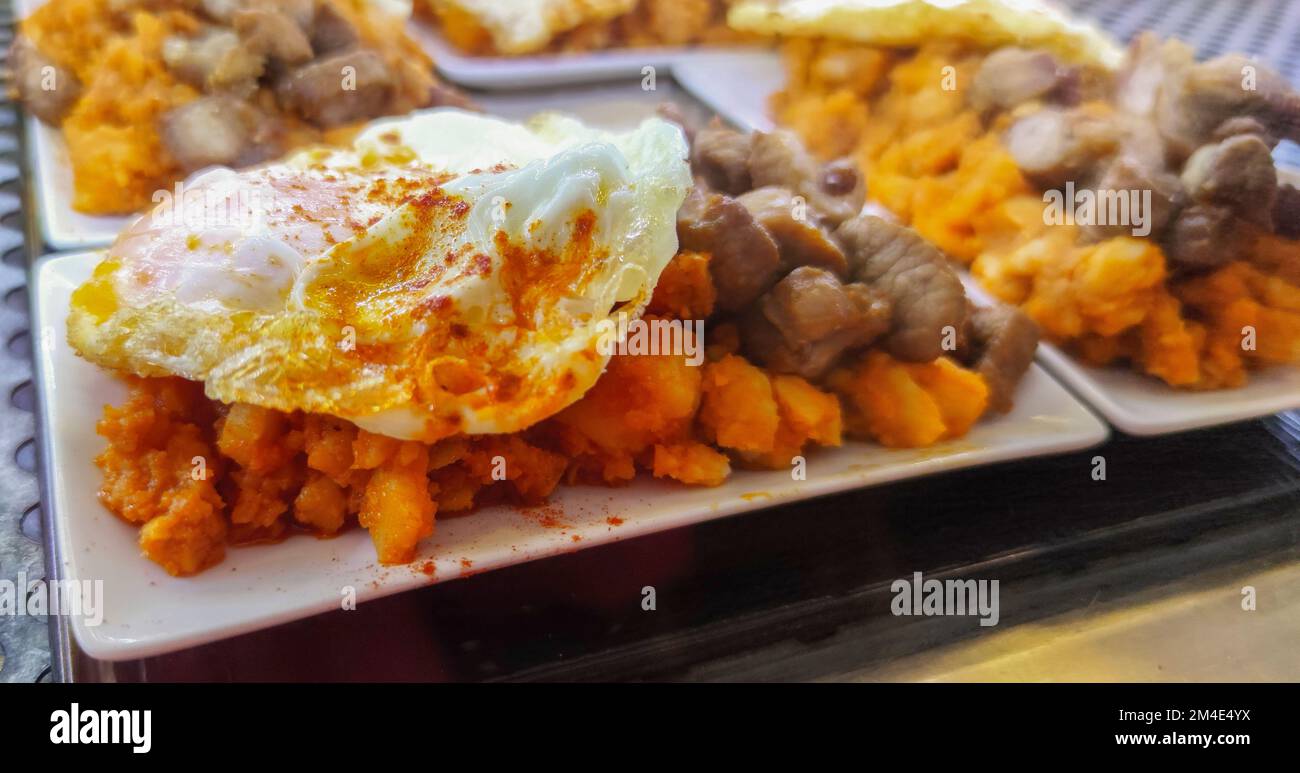 Pommes de terre brouillés avec œuf et filet de bœuf frits. Servi au comptoir à tapas Banque D'Images