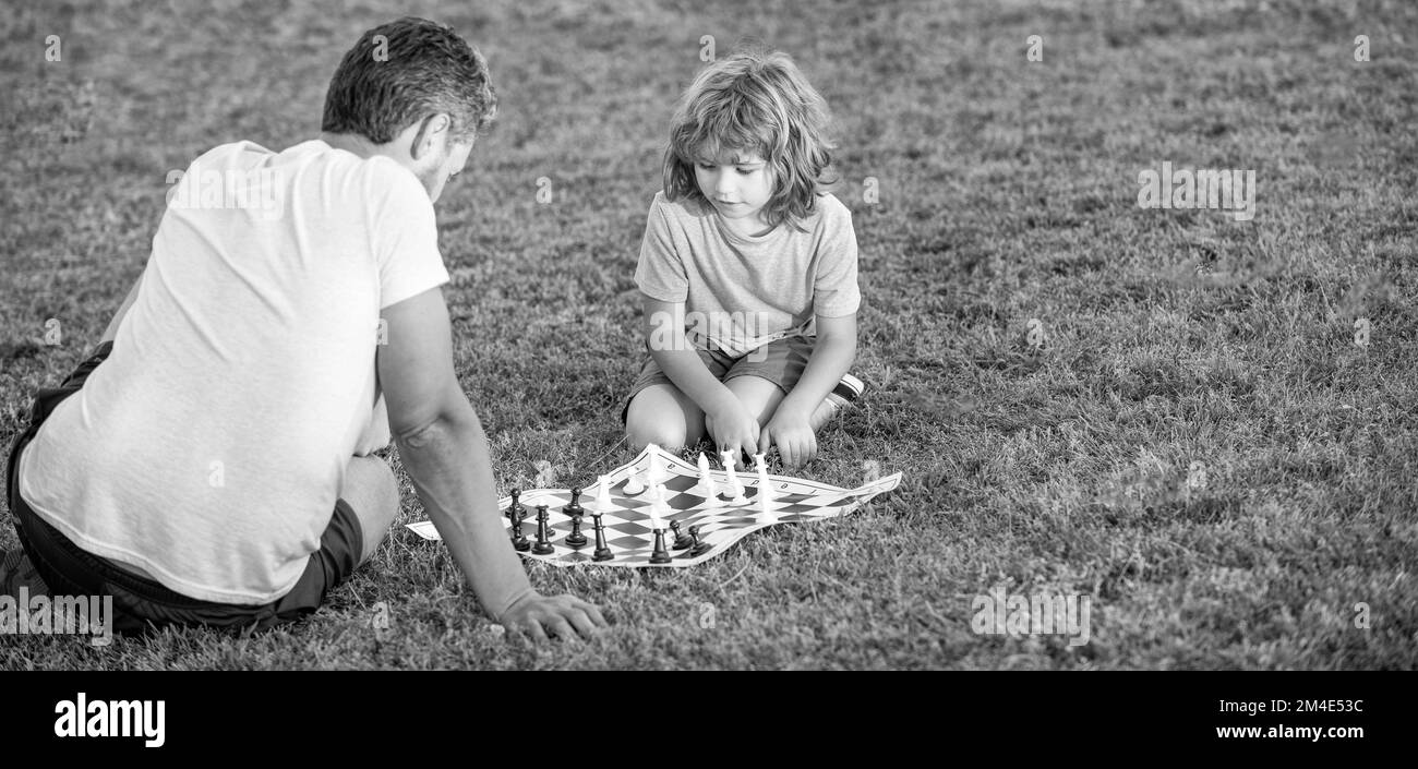 papa et gamin jouent au jeu logique. espace de copie. père et fils jouant aux échecs dans le parc. fête des pères. Banque D'Images