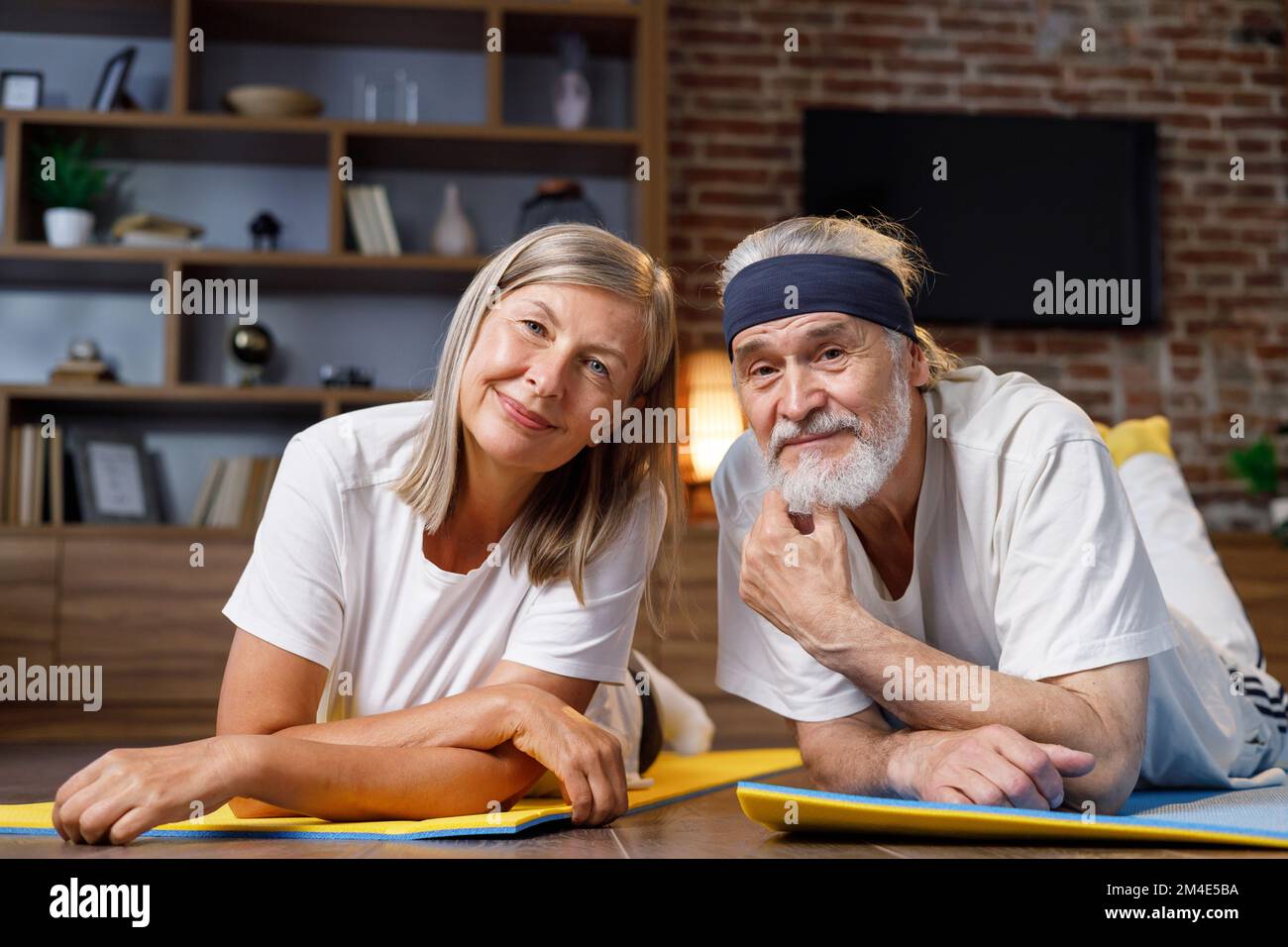 Heureux à cheveux gris mature couple âgé faisant de la gymnastique ensemble à la maison. Un mode de vie actif et sain pour les retraités. Fitness, loisirs, bien Banque D'Images