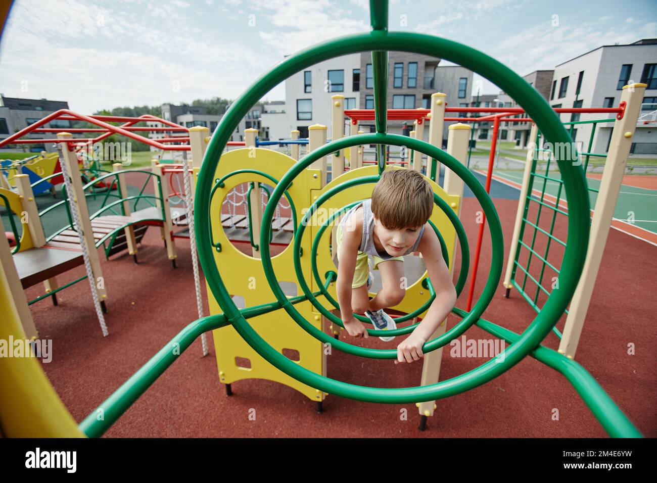 Vue grand angle d'un jeune garçon jouant dans la jungle gym sur un terrain de jeu coloré, espace de copie Banque D'Images