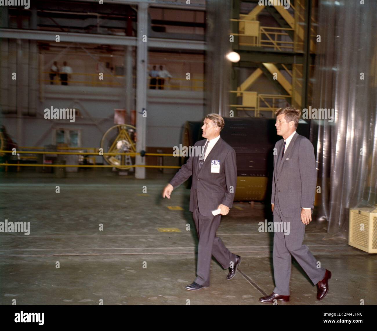Le président John F Kennedy et Werner von Braun marchent ensemble dans un laboratoire de recherche sur l'exploration spatiale pendant la course à l'espace. Banque D'Images