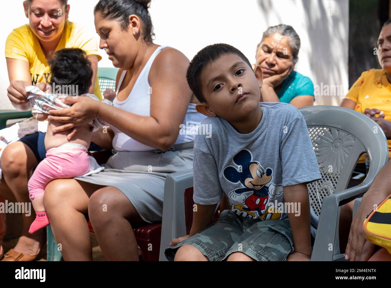 La Labor, la Libertad, Salvador - 27 octobre 2022 - Un garçon salvadorien regarde la caméra tandis que sa mère et d'autres femmes attendent le Reu Banque D'Images