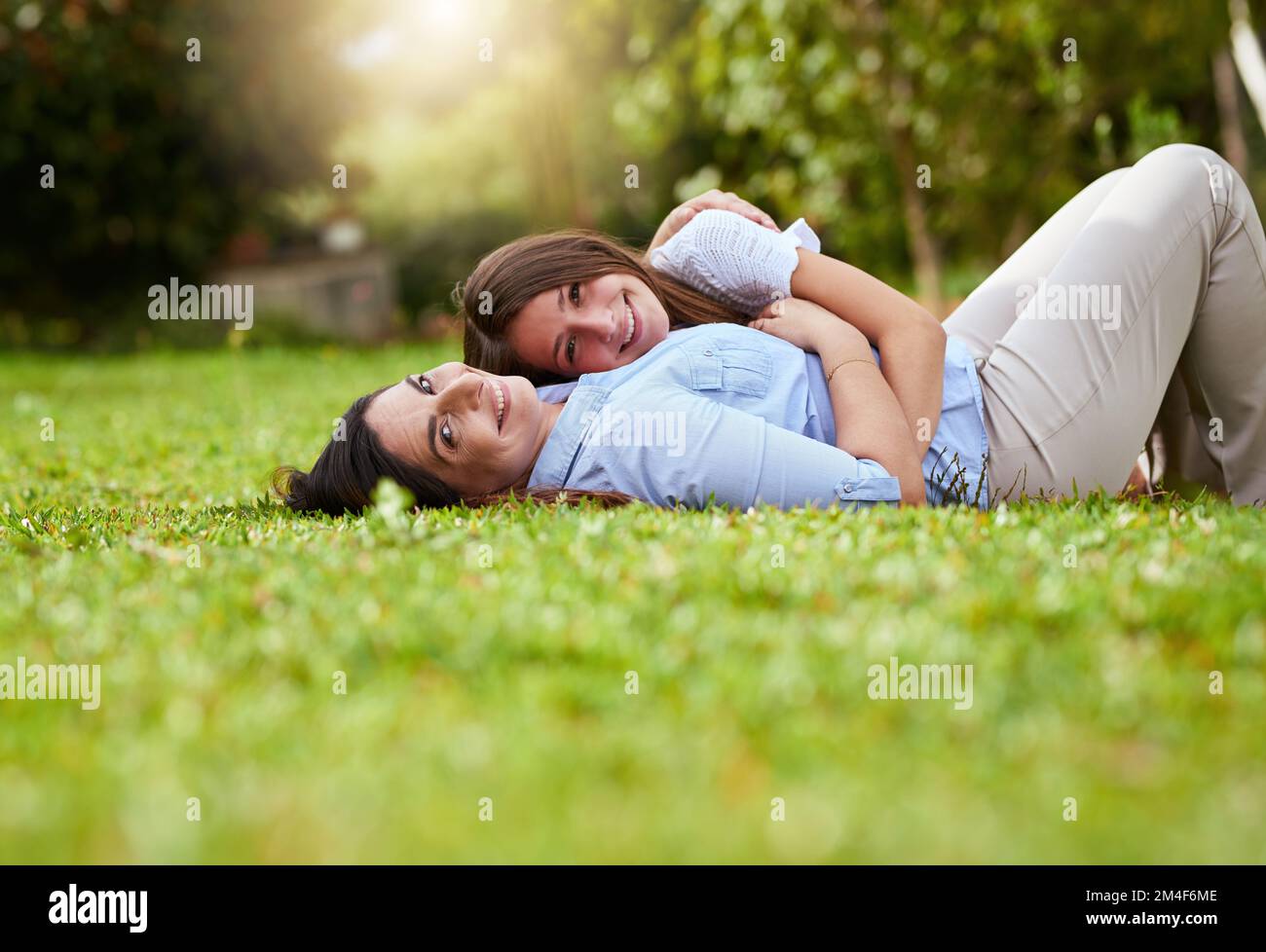 Ils se ressemblent. Portrait d'une mère gaie et de sa jeune fille allongé sur l'herbe à l'intérieur d'un parc à l'extérieur pendant la journée. Banque D'Images