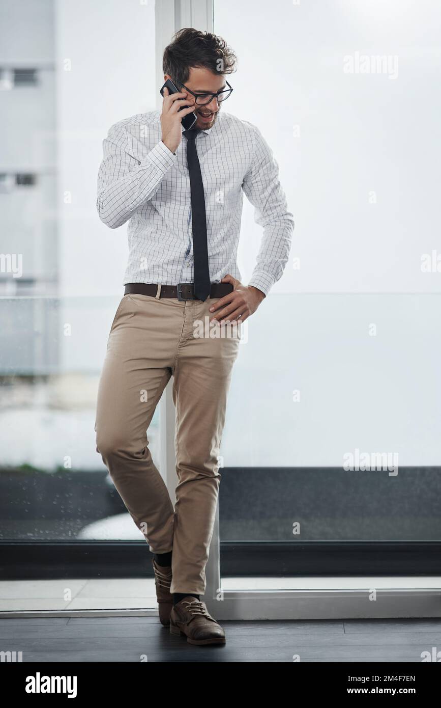 Il met toujours ses clients en premier. un jeune homme d'affaires parlant sur un téléphone portable dans un bureau. Banque D'Images