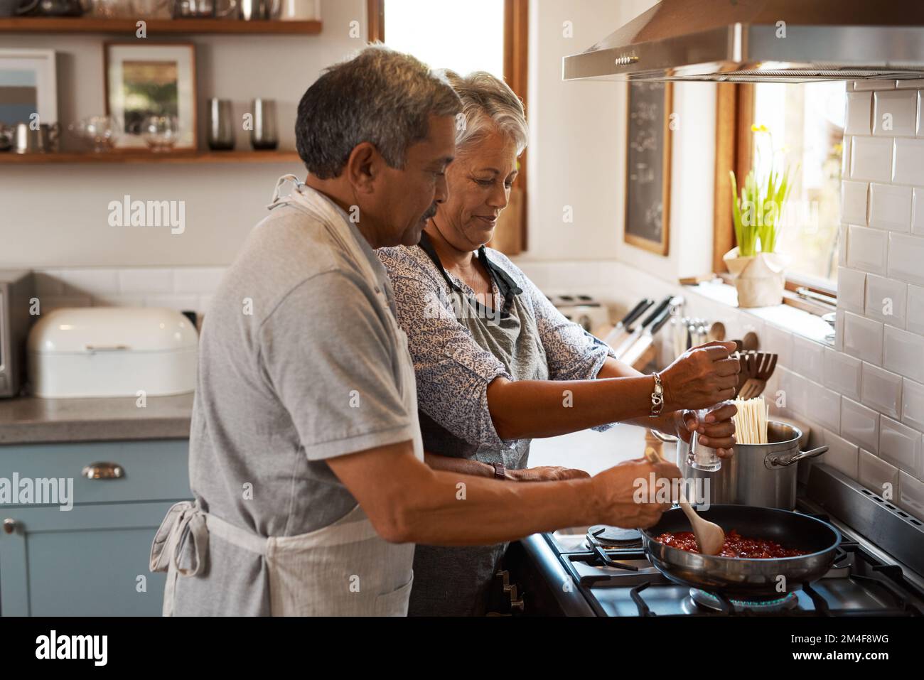 Le sel n'est pas le seul ingrédient spécial. un heureux couple mature qui prépare un repas à la maison. Banque D'Images