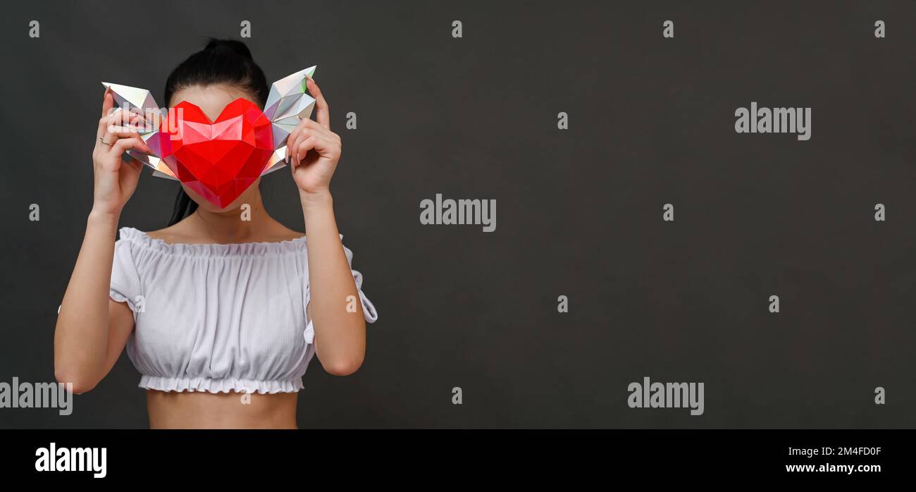 banner girl tient un coeur polygonal avec des ailes dans ses mains. isolé sur un fond gris. maquette Banque D'Images