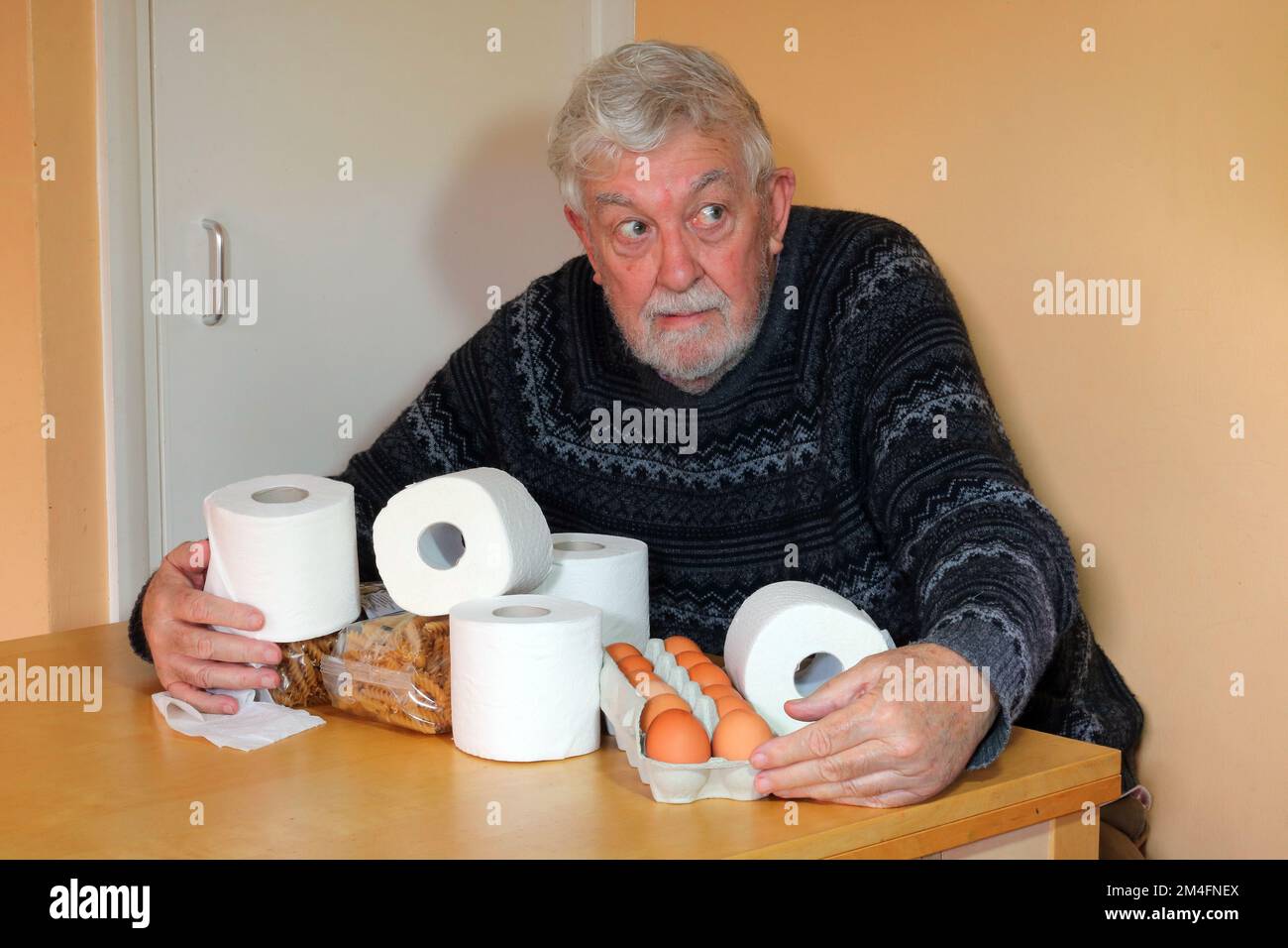 Homme âgé ou âgé très heureux d'avoir une arge de rouleaux de toilettes. Collecte des rouleaux de toilettes en cas de pénurie, possessif à leur sujet. Banque D'Images