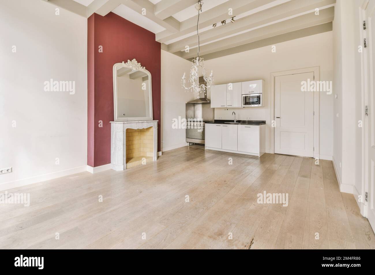 un salon vide avec parquet et murs rouges, armoires blanches et un grand miroir suspendu au mur Banque D'Images