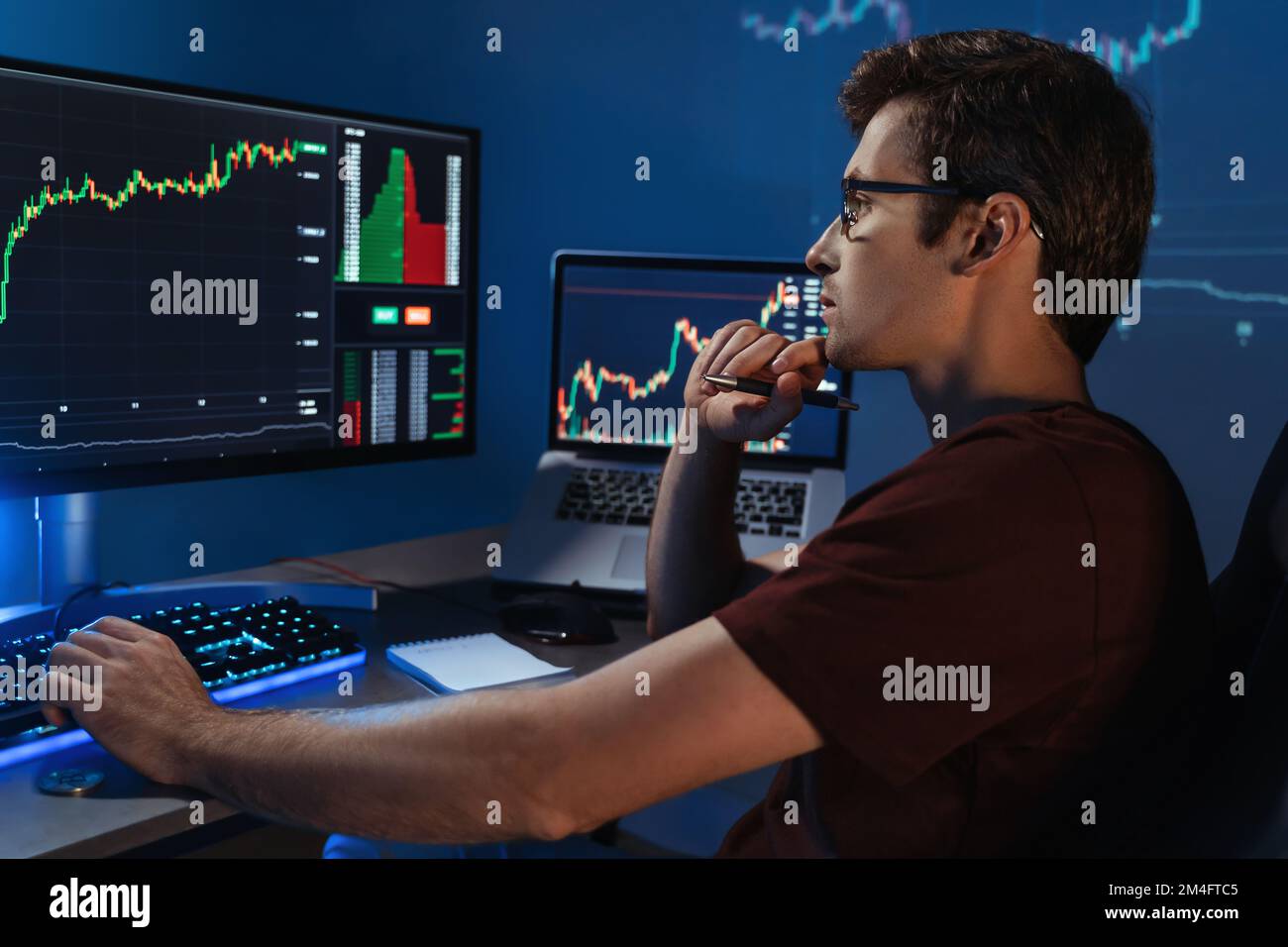 Gros plan sur le côté de beau crypto-expert intelligent touchant le menton avec la main, travaillant en ligne assis à la maison de bureau, analysant la volatilité du marché des changes Banque D'Images