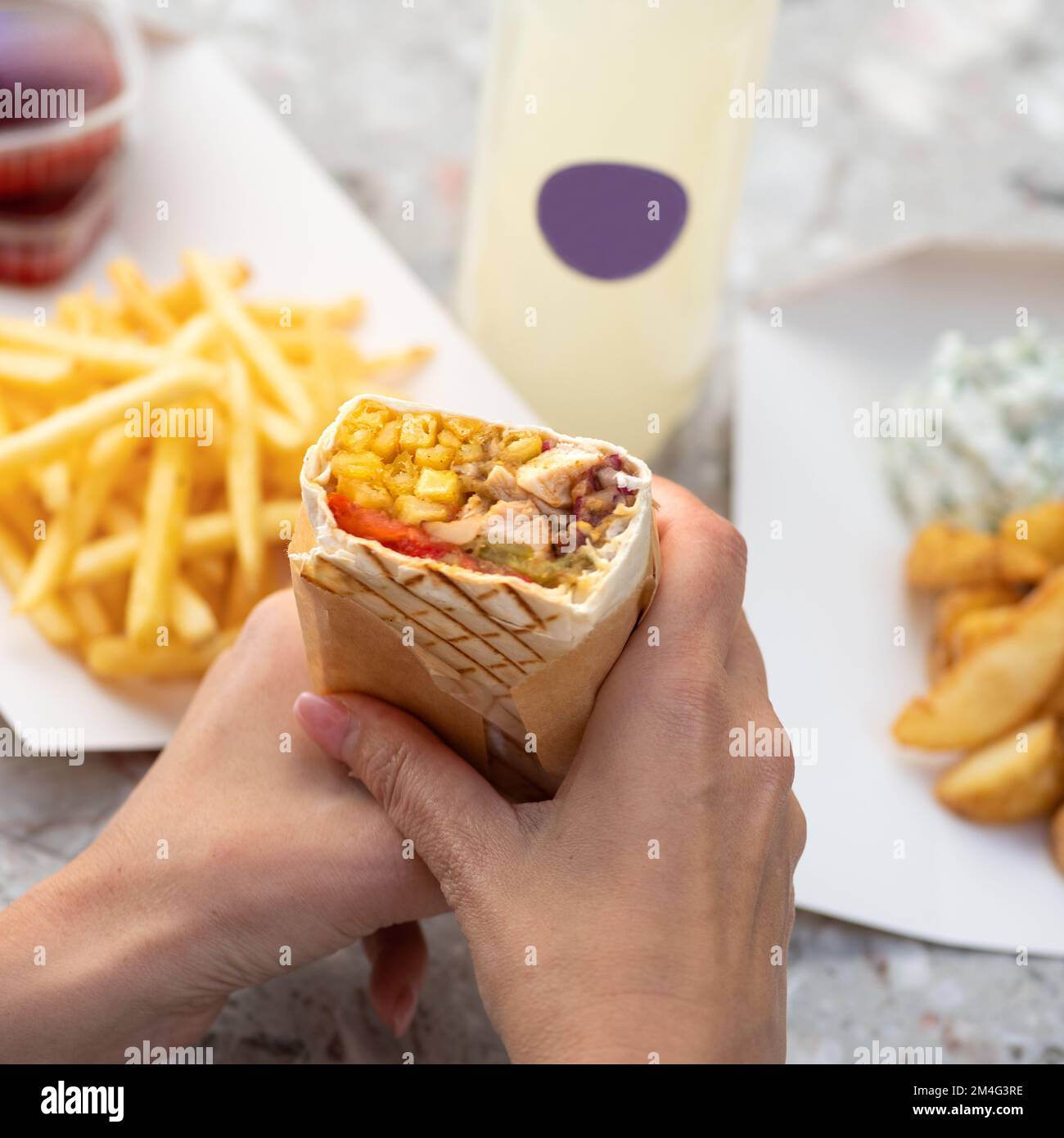 Sandwich Gyro shawarma pain pita frais dans les mains des femmes. Plats à emporter traditionnels du Moyen-Orient. Banque D'Images