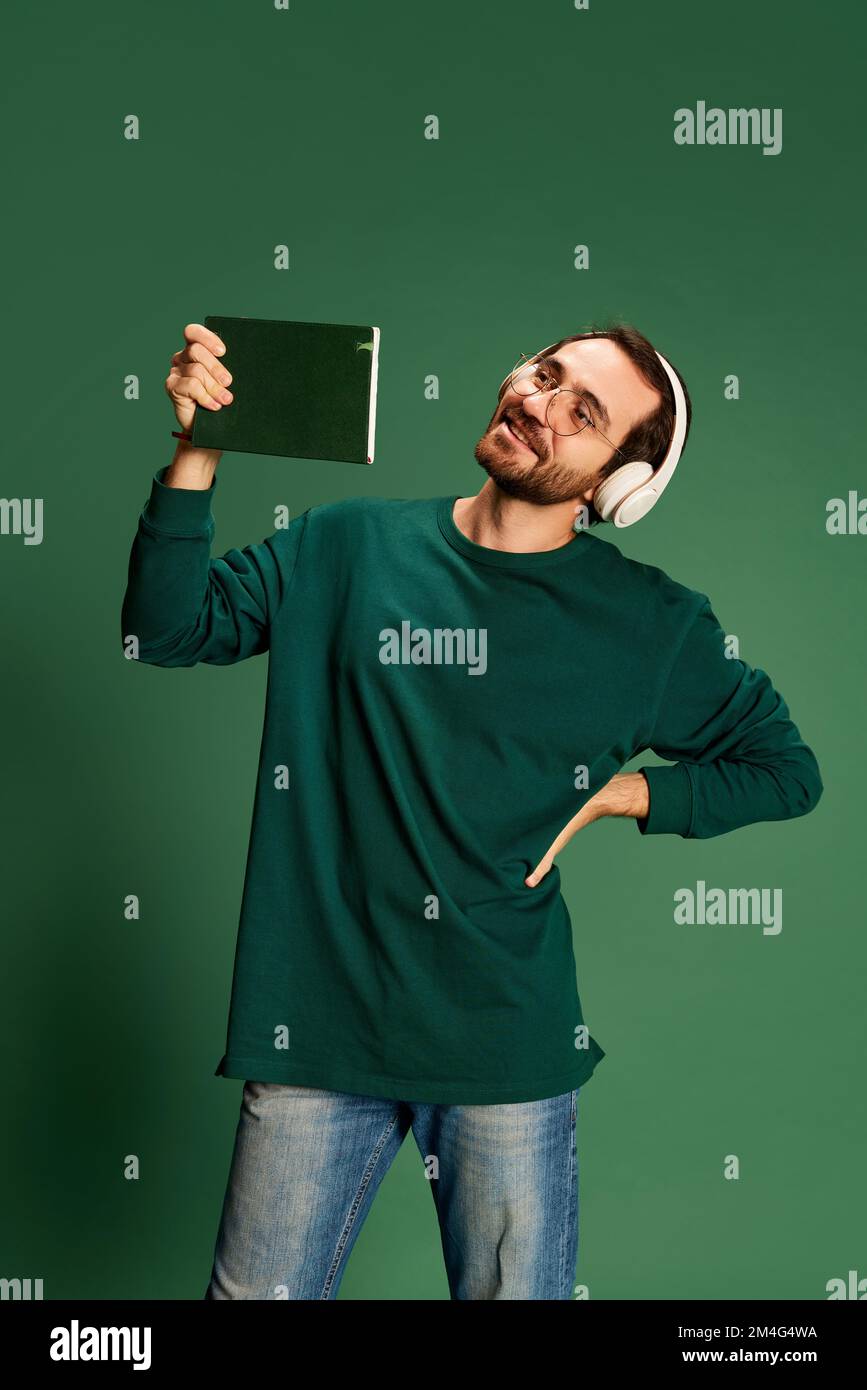 Portrait d'un jeune beau homme heureux avec une barbe portant un pull décontracté et des lunettes sur fond vert. Bonheur, émotions positives Banque D'Images