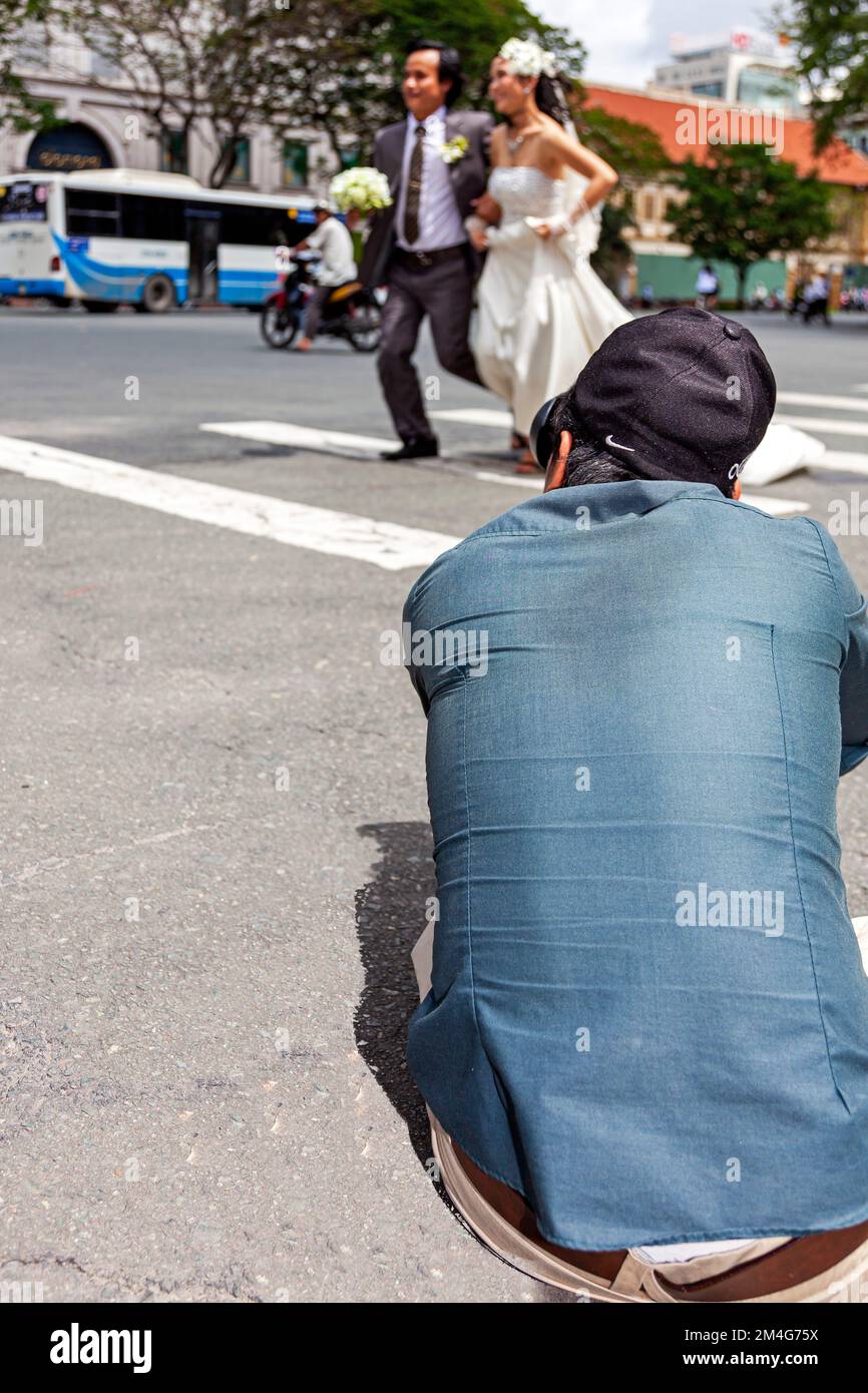 Photographe de mariage vietnamien prenant la photo d'un couple en face de la rue, centre de Ho Chi Minh ville, Vietnam Banque D'Images