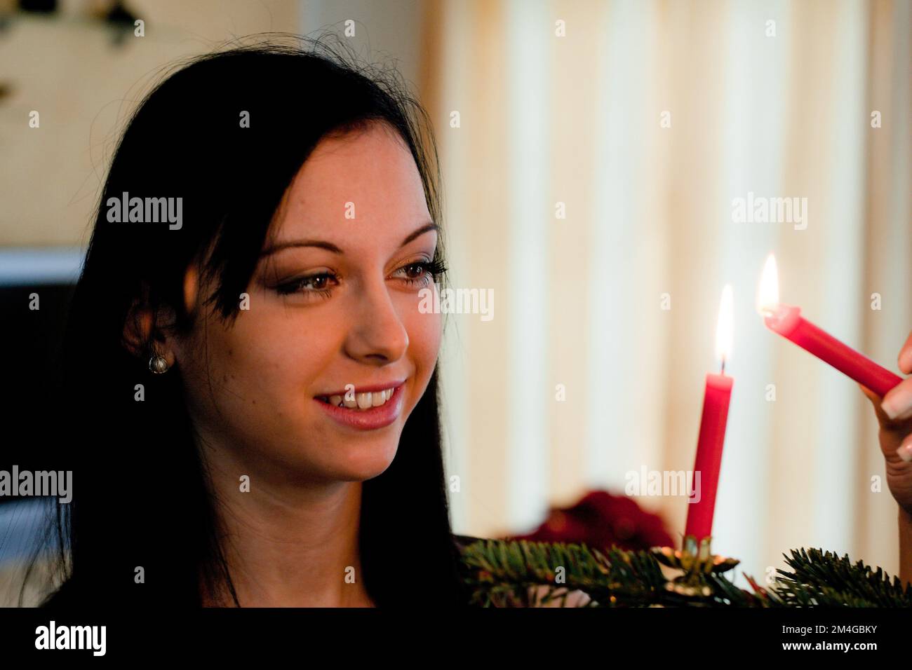 Jeune femme allumant les bougies sur l'arbre de Noël Banque D'Images
