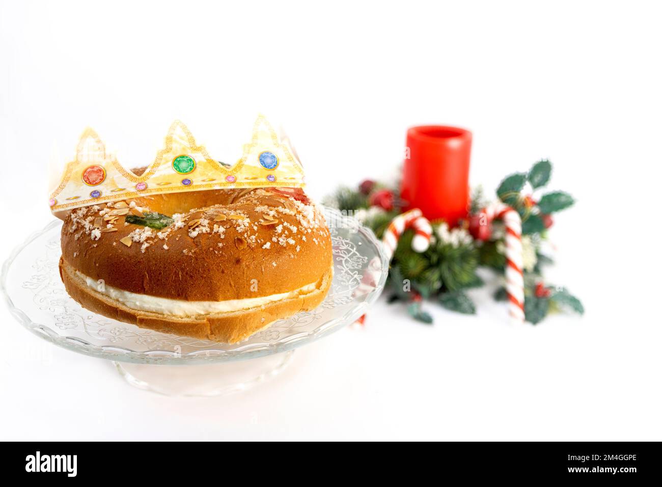 Roscon de reyes sur une assiette avec cannes de noël et bougie rouge sur fond blanc, dessert typique de l'Espagne en janvier trois rois jour Banque D'Images