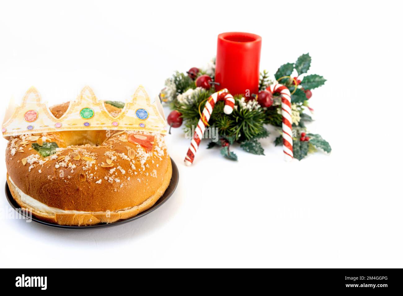 Roscon de reyes sur une assiette avec cannes de noël et bougie rouge sur fond blanc, dessert typique de l'Espagne en janvier trois rois jour Banque D'Images