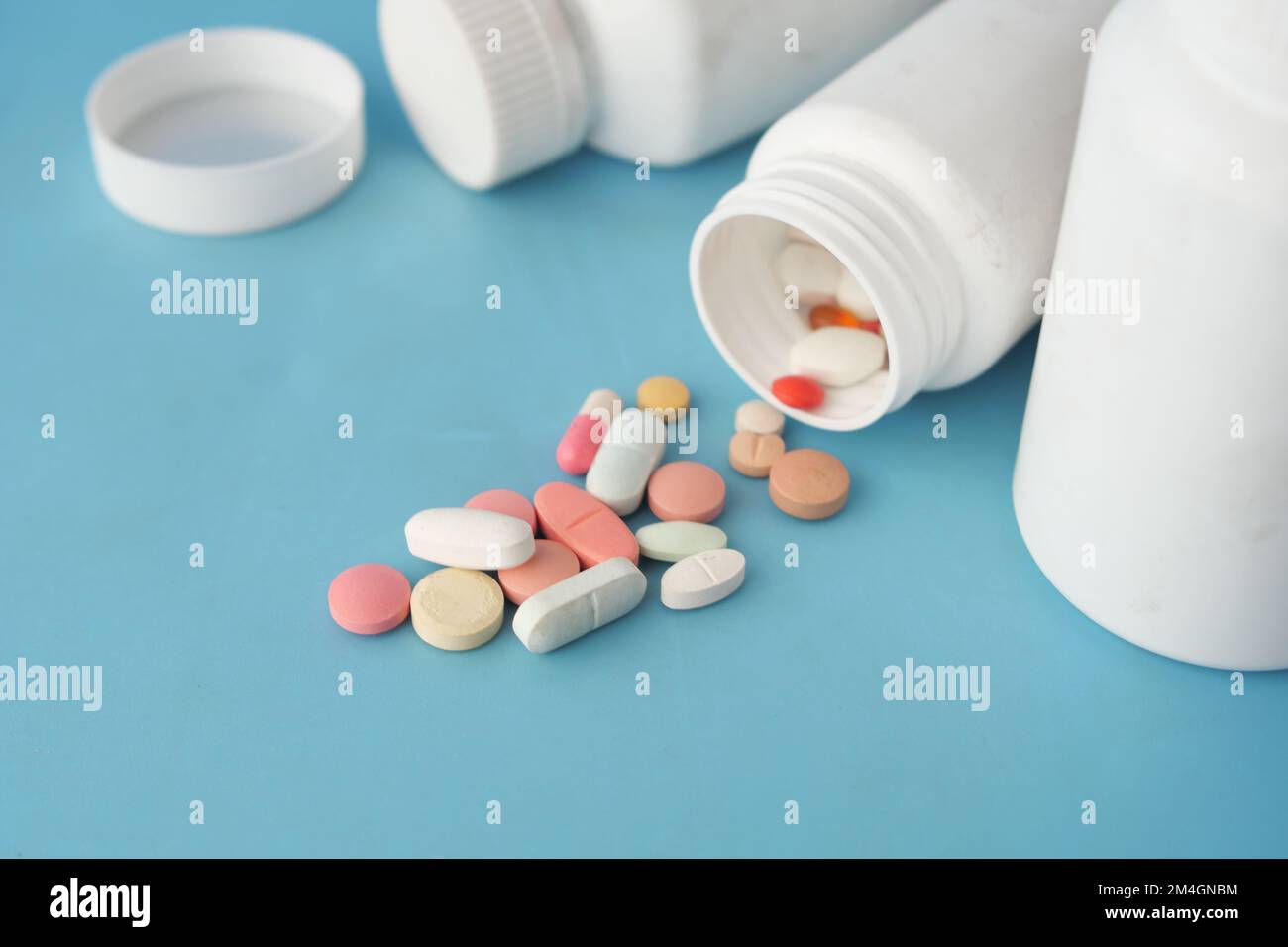 des pilules médicales et une capsule débordent sur fond bleu Banque D'Images