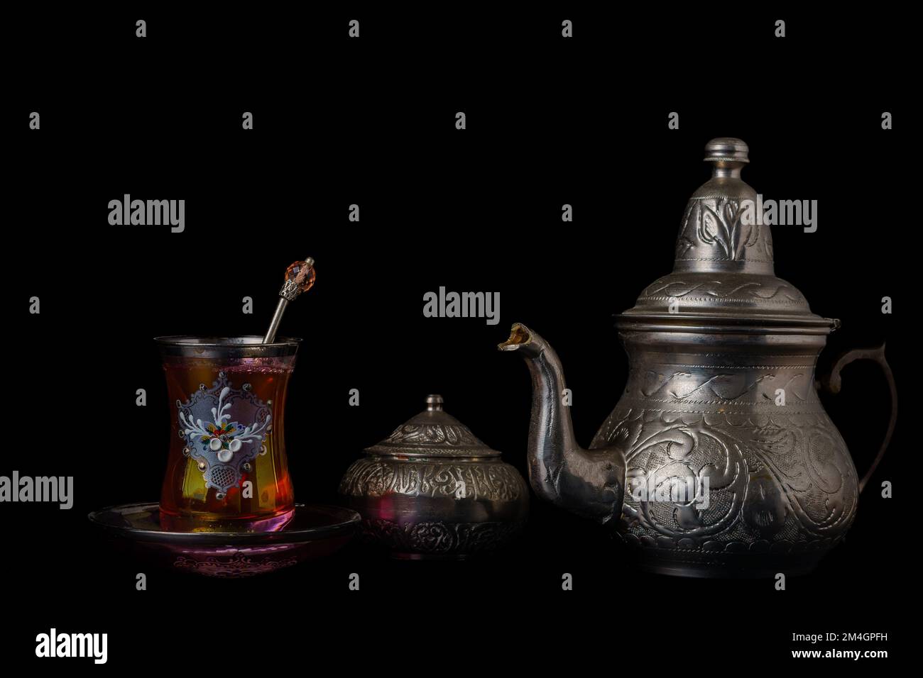 tasse à thé décorée d'une théière et d'un bol à sucre en métal isolé sur fond noir Banque D'Images