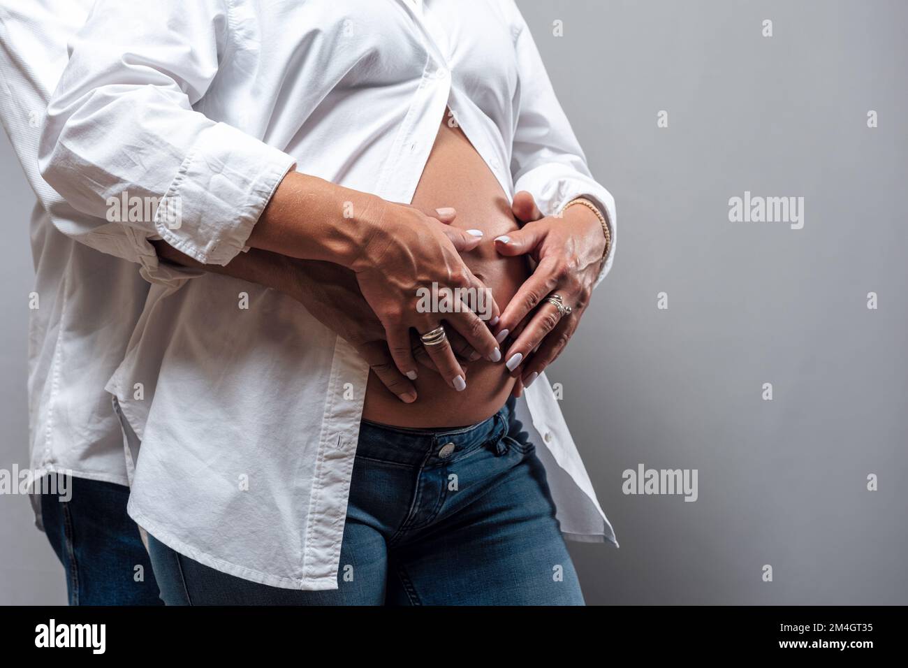Les mains des hommes et des femmes épousent le ventre d'une femme enceinte. Grossesse, maternité, préparation et concept d'attente. Banque D'Images