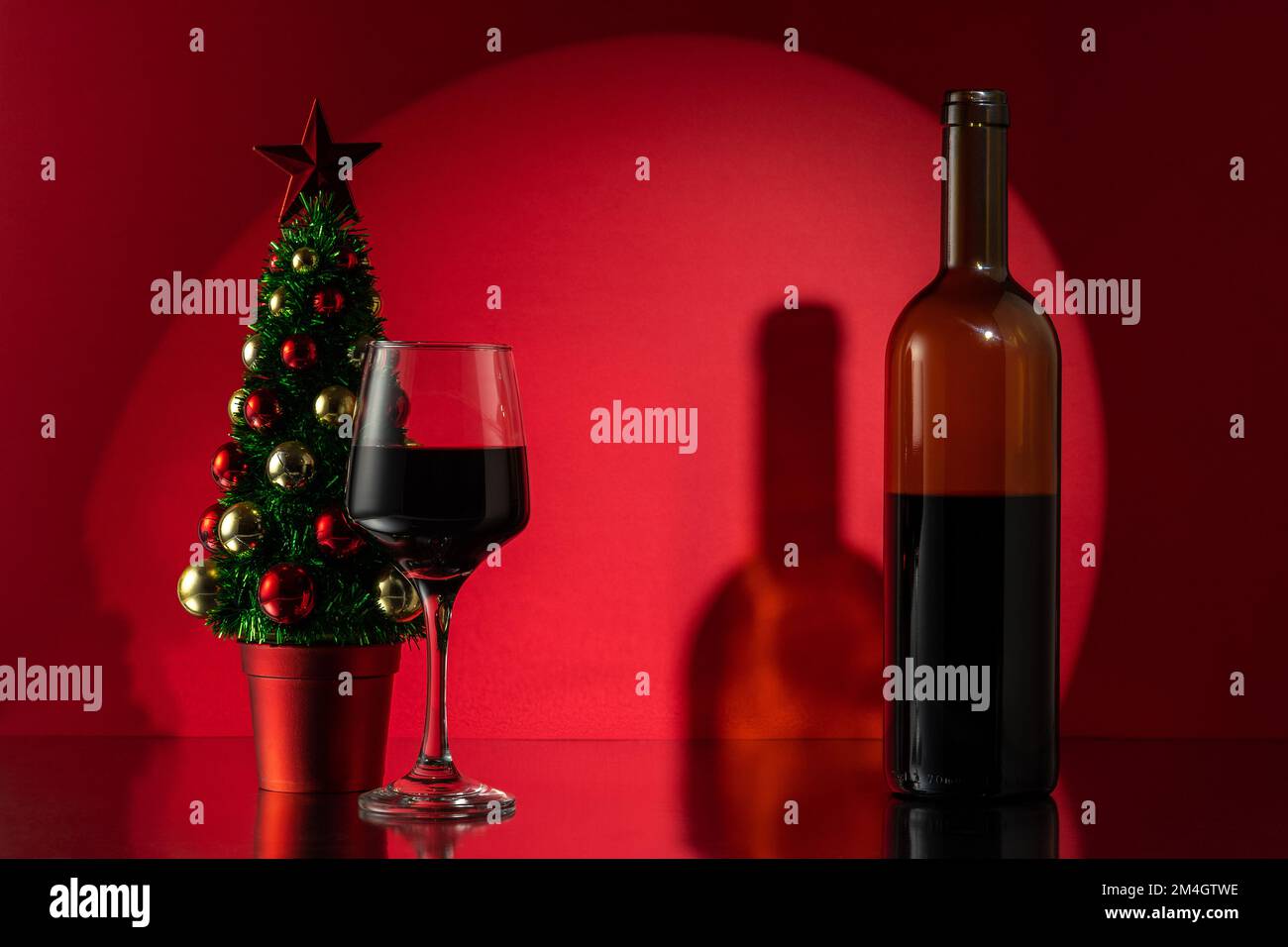 Arbre de Noël avec bouteille de vin rouge sur fond de mur rouge. Concept nouvel an ou Noël. Banque D'Images