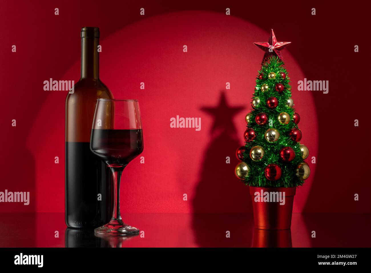 Arbre de Noël avec bouteille de vin rouge sur fond de mur rouge. Concept nouvel an ou Noël. Banque D'Images