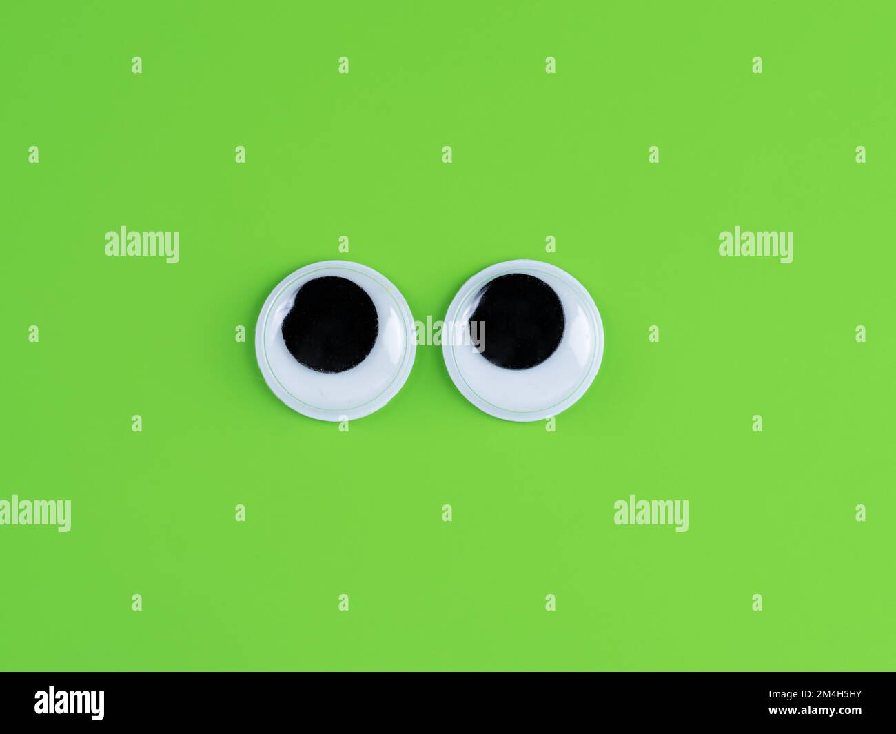 Googly cute yeux drôle isolé sur fond vert lime brillant copier espace logo Banque D'Images