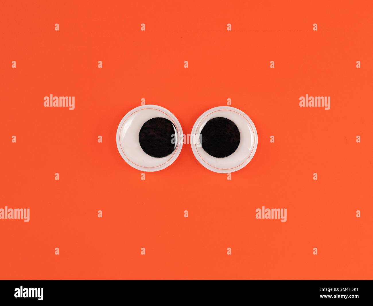 Adorable yeux googly drôle isolé sur fond orange vif copie espace logo Banque D'Images