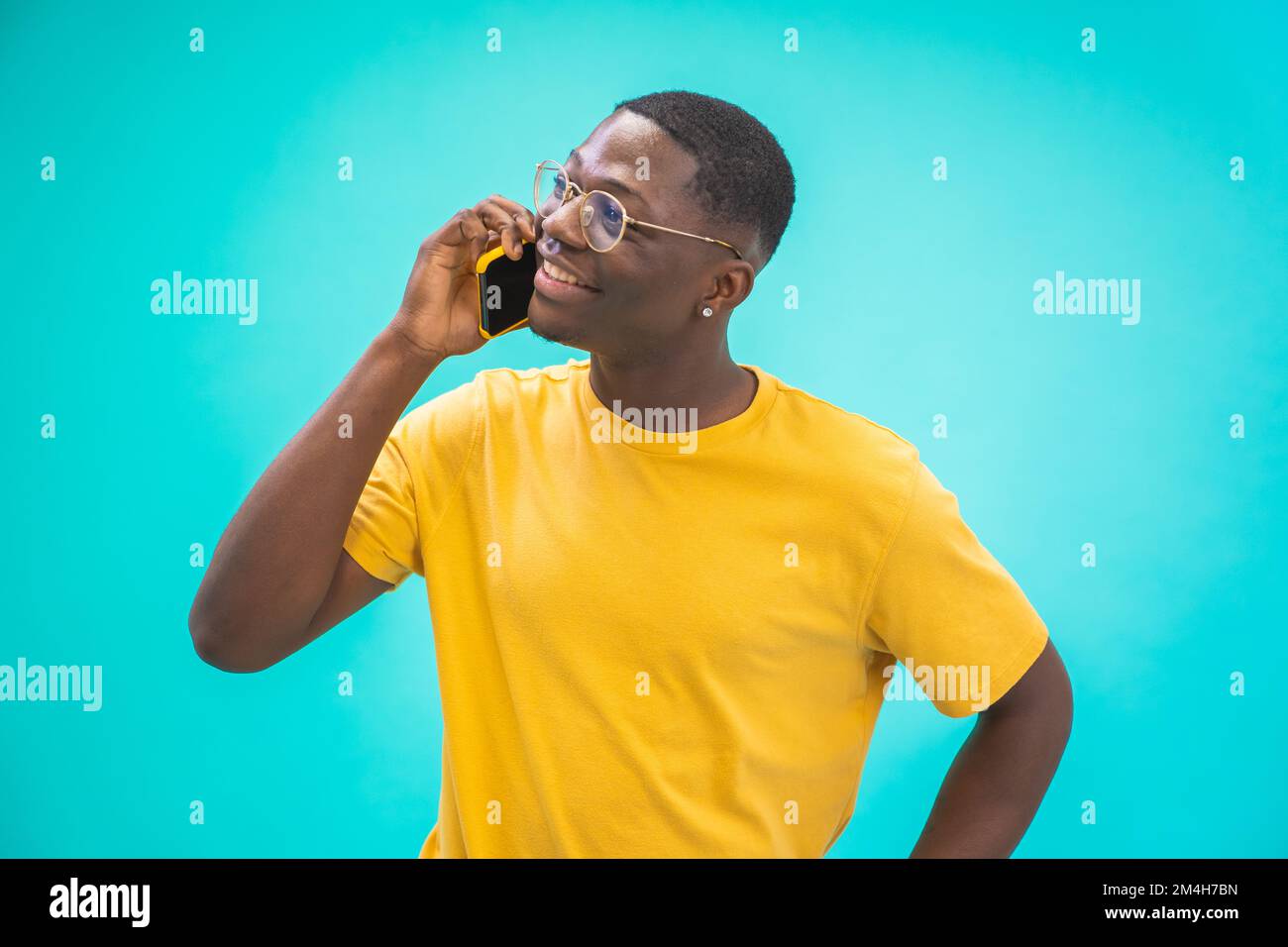 Attrayant noir gars africain parlant sur le téléphone portable sourire heureux isolé sur fond bleu. Banque D'Images