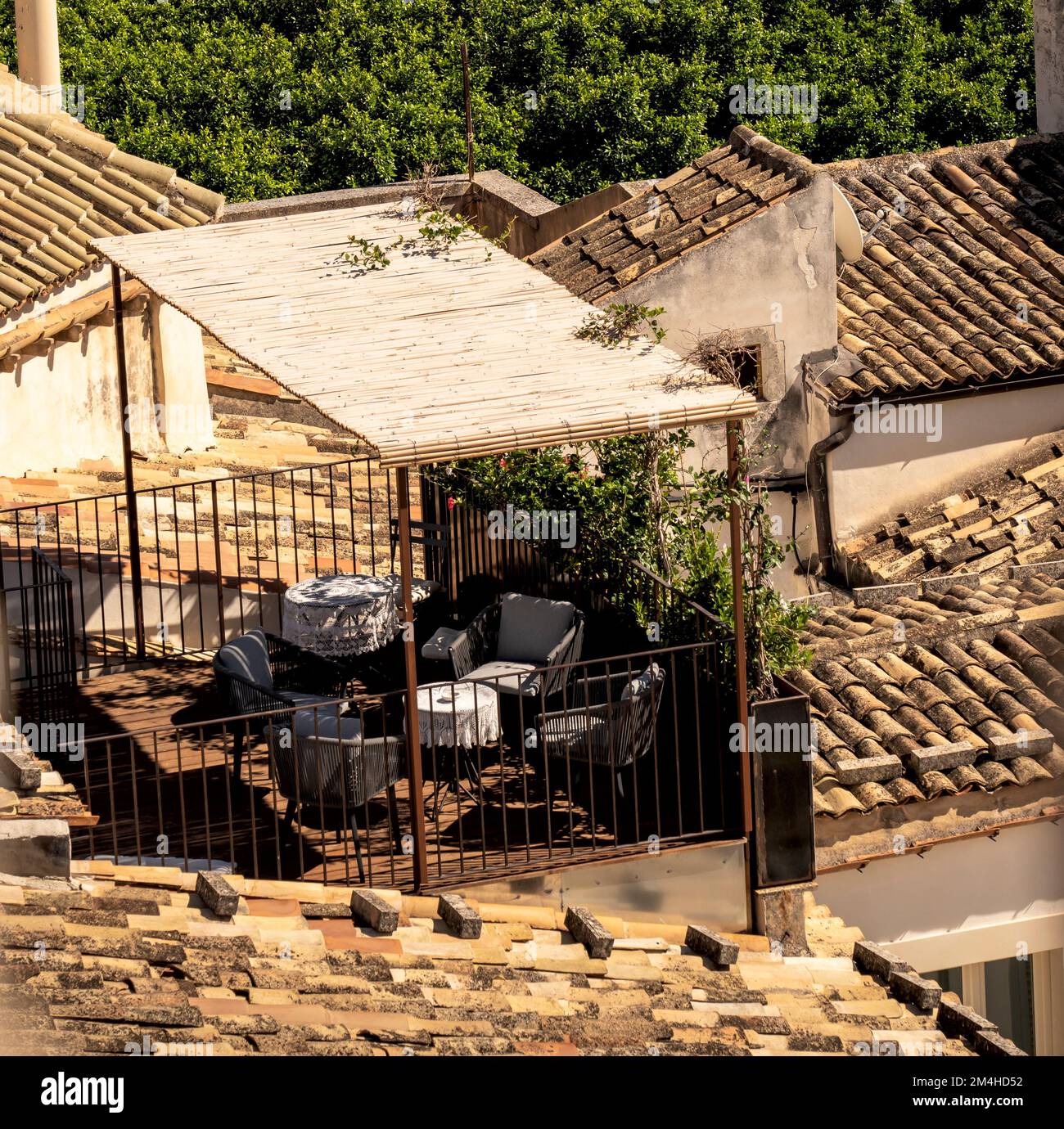 noto, sicile, italie 09-24-2022: petite terrasse meublée d'un salon de jardin à l'ombre du soleil d'été, entourée de toits carrelés Banque D'Images