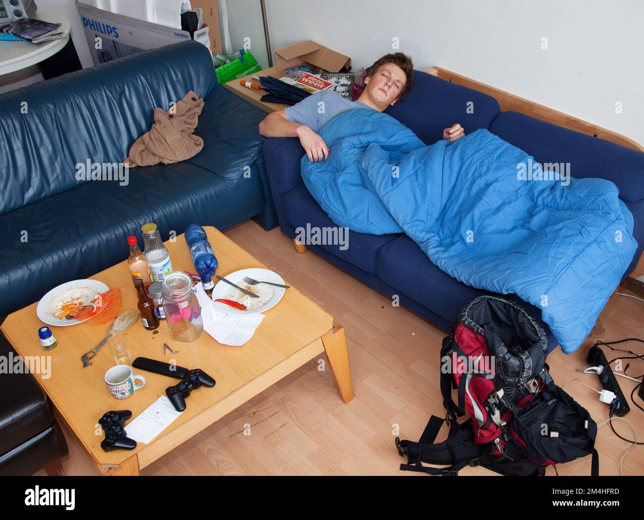 Pays-Bas, Amsterdam. Un garçon rend visite à un ami et dort sur un canapé. Il s'appelle couchsurfing. Banque D'Images
