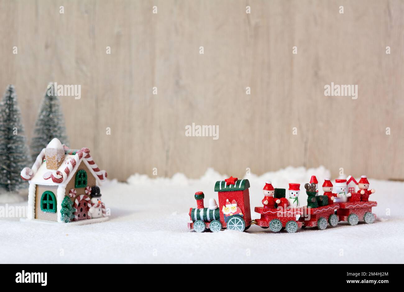 Scène de Noël. Un train de Noël en bois rouge traverse la neige artificielle vers la maison du Père Noël. Banque D'Images