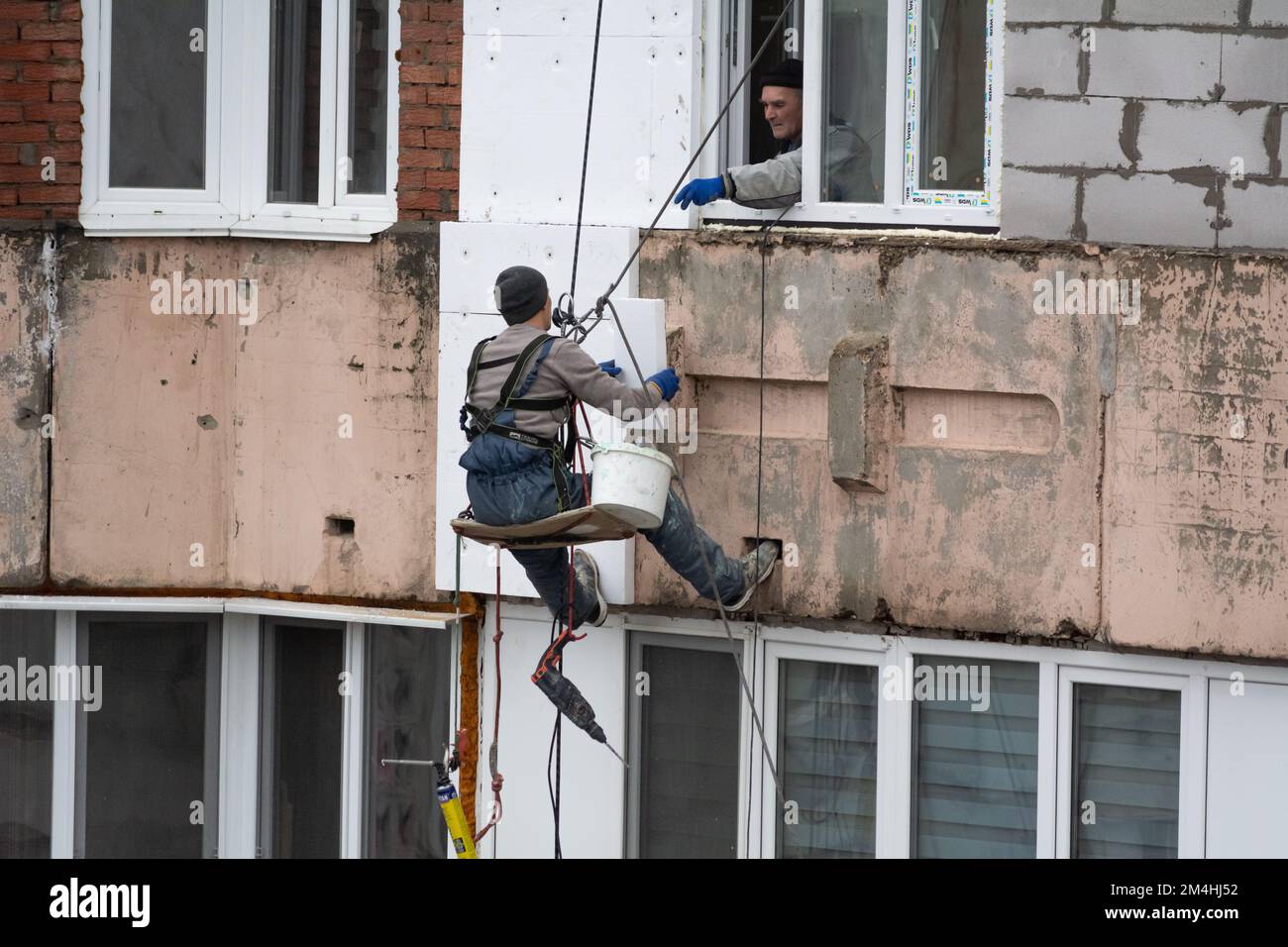 Tiraspol, Moldavie - 10 décembre 2022 : un constructeur de haute altitude isole la façade d'un immeuble d'appartements en plastique mousse. Maison isolante aérée Banque D'Images
