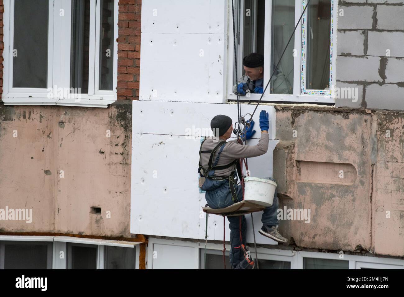 Tiraspol, Moldavie - 10 décembre 2022 : un constructeur de haute altitude isole la façade d'un immeuble d'appartements en plastique mousse. Maison isolante aérée Banque D'Images