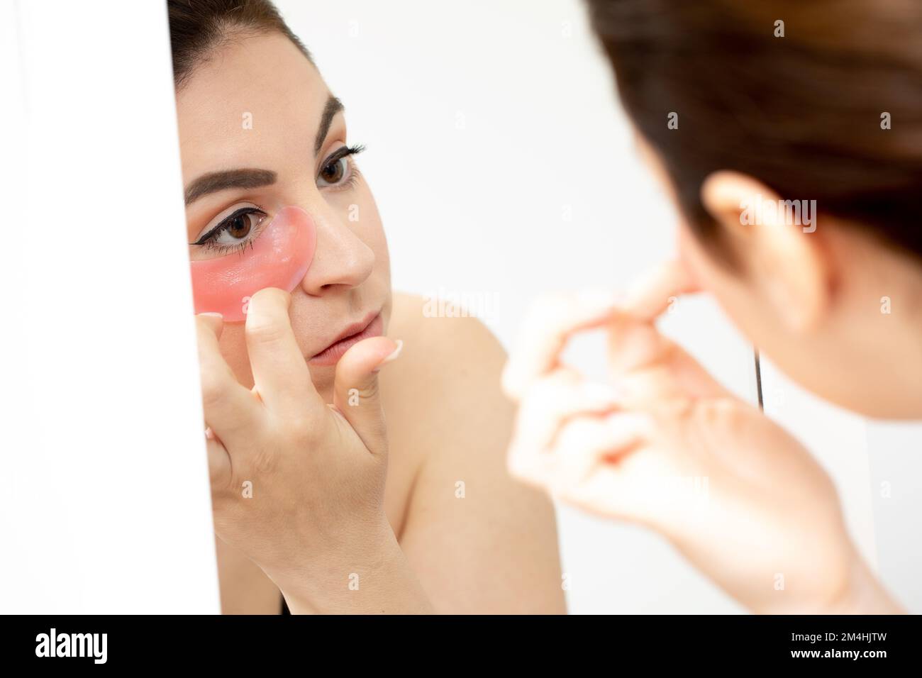Femme dans le miroir avec masque contour des yeux. Patch hydratant pour éliminer la puffinité, les cercles sombres et les rides sous les yeux Banque D'Images