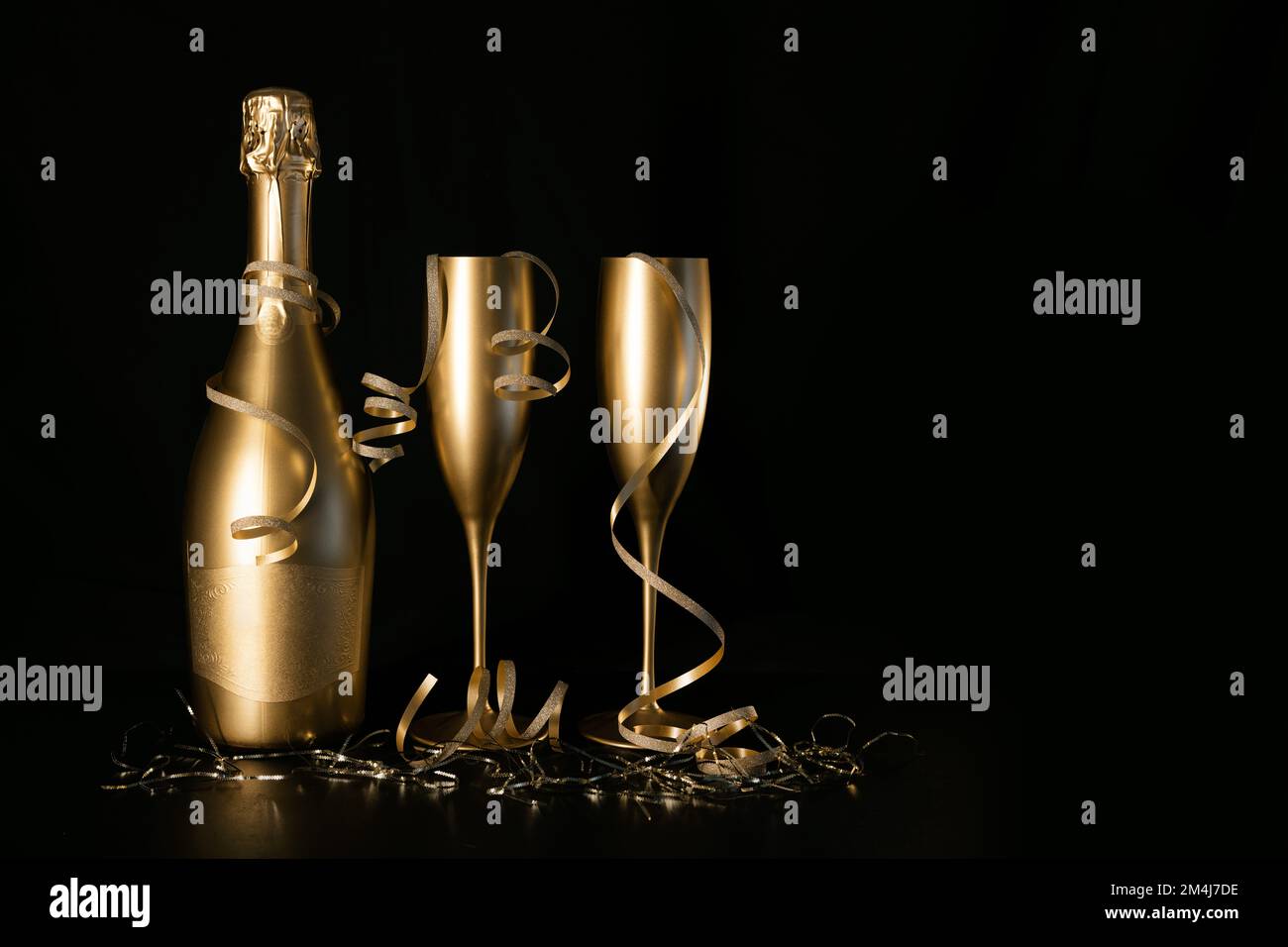 bouteille de champagne dorée et deux verres avec rubans sur fond noir avec espace pour les copies. fête du nouvel an et célébration d'anniversaire Banque D'Images
