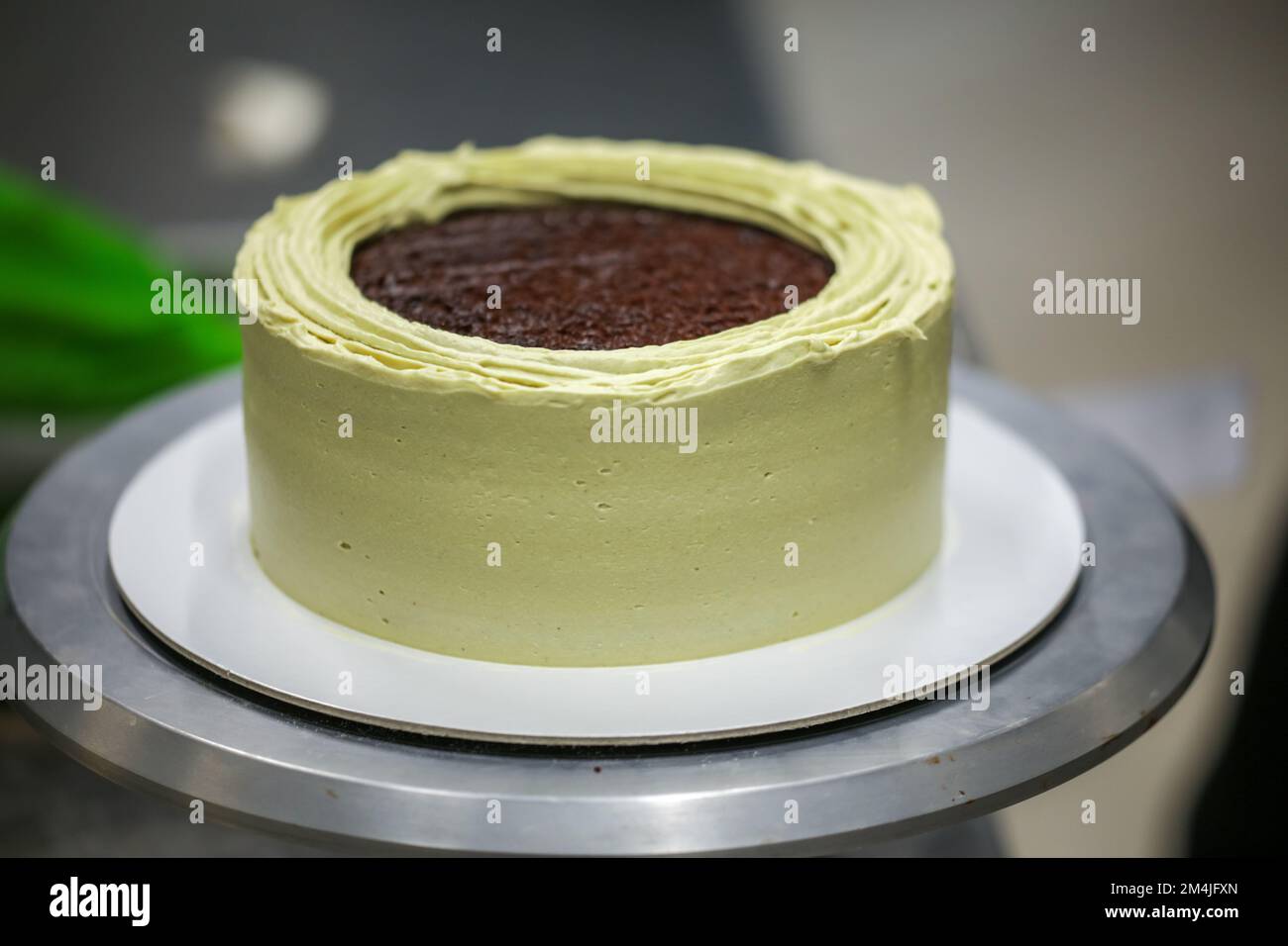 Décorateur à l'aide d'une spatule et d'un grattoir pour lisser la crème de  beurre sur un gâteau dépoli Photo Stock - Alamy