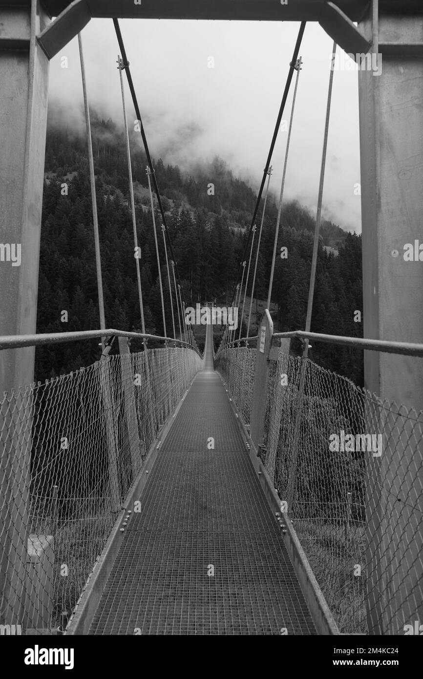 Un cliché en niveaux de gris d'un pont suspendu dans les Alpes autrichiennes Banque D'Images