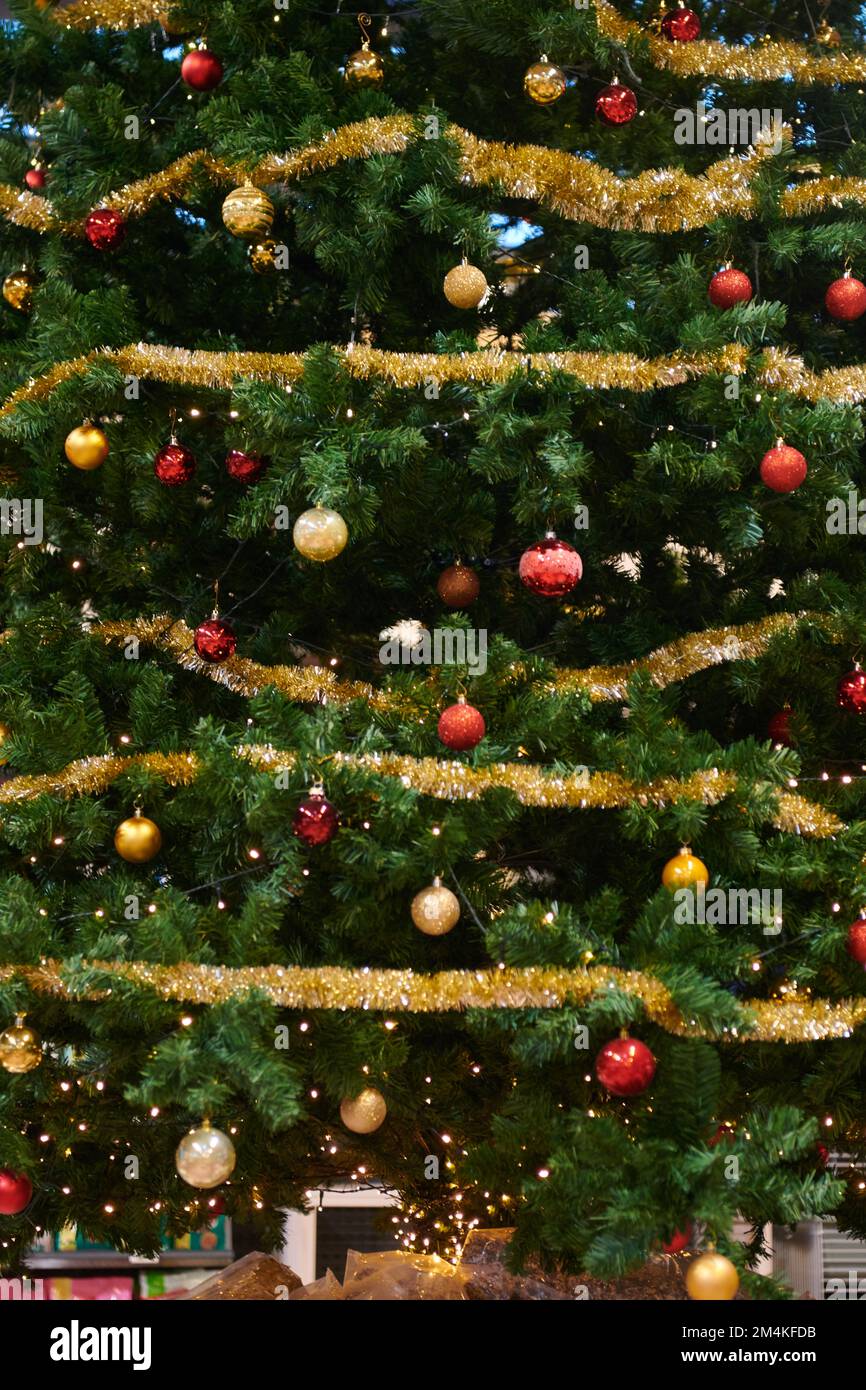 Un gros plan vertical d'un arbre de Noël avec des boules dorées et rouges,  guirlande scintillante et guirlande lumineuse Photo Stock - Alamy