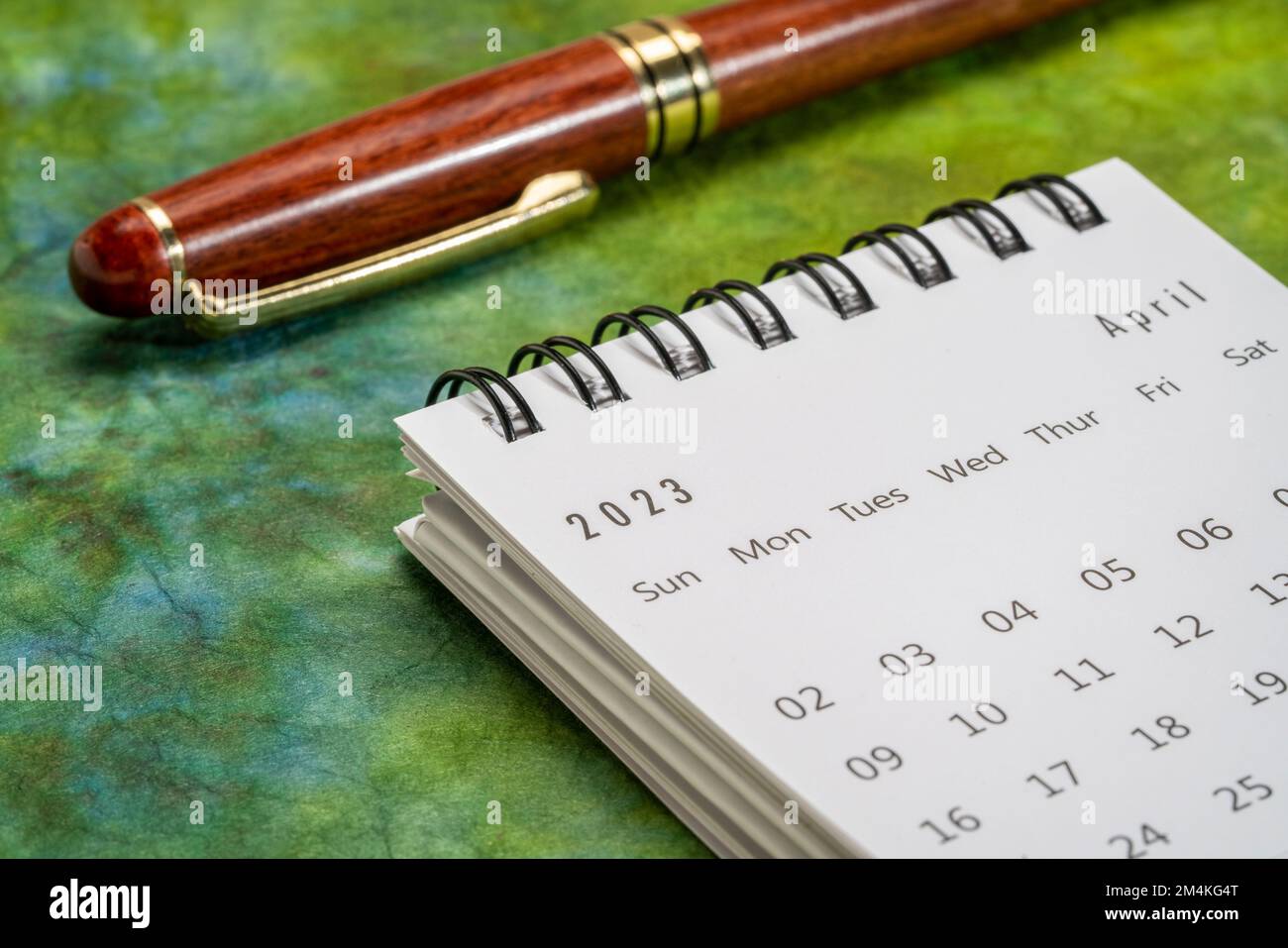 Avril 2023 - petit calendrier de bureau en spirale avec un stylo élégant contre le papier marbré, le temps et le concept d'entreprise Banque D'Images