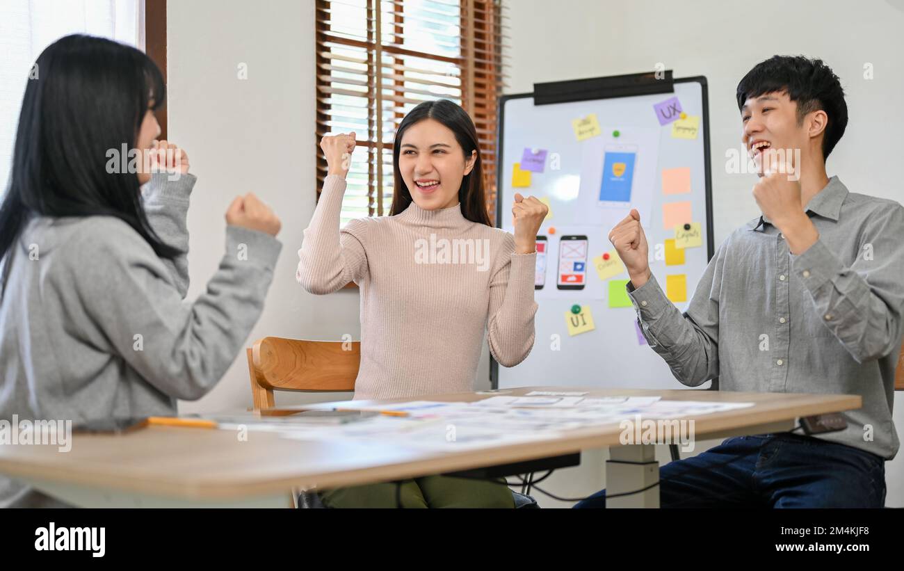 Des développeurs asiatiques joyeux et enthousiastes célèbrent leur succès ensemble dans la salle de réunion. travail d'équipe, coordination, réussi Banque D'Images