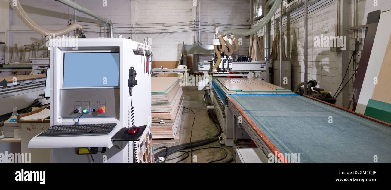 Armoire de commande de système à écran bleu avec clavier et souris dans une usine industrielle produisant des pièces de meubles en bois. Banque D'Images