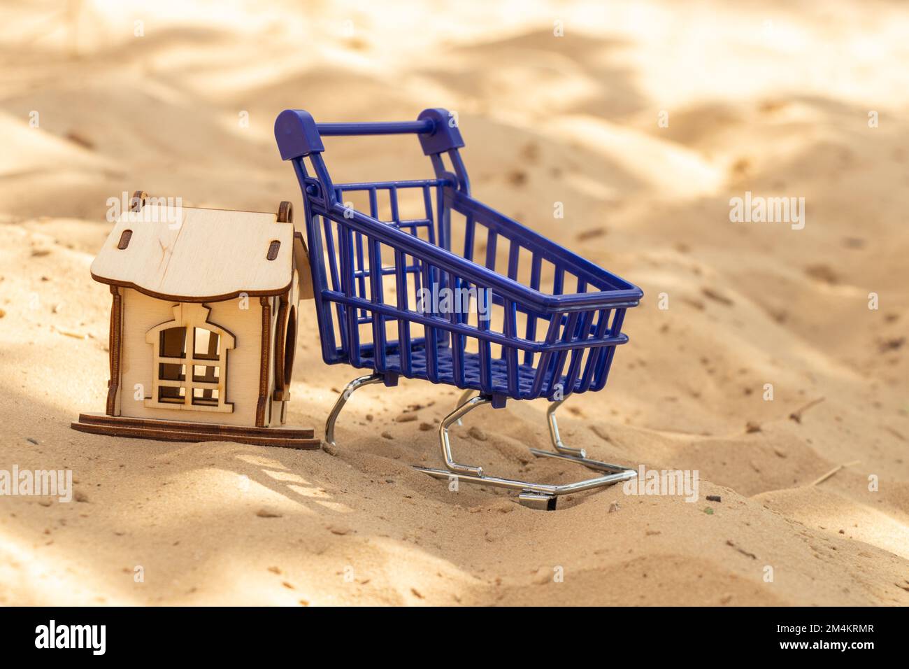 petite maison en bois et chariot bleu avec supermarché sur le sable Banque D'Images