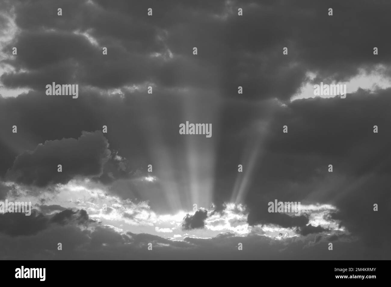 Coucher de soleil spectaculaire avec des nuages sombres et des aperçus de lumière, rayons de soleil entre les nuages, photo noir et blanc. Banque D'Images