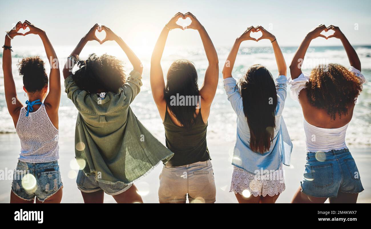 Les amis rendent le monde magnifique. Vue arrière d'un groupe de filles montrant des formes de coeur avec leurs mains. Banque D'Images