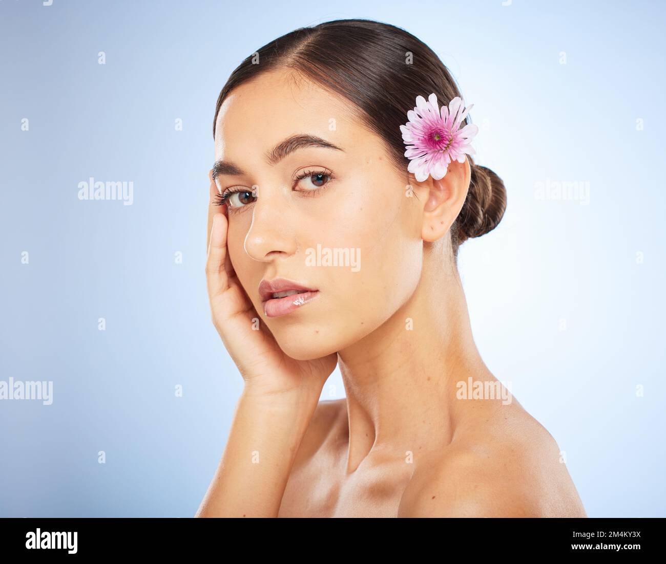 Femme, visage et portrait de beauté avec fleur dans les cheveux pour le bien-être de soin de la peau ou la dermatologie de cosmétiques naturels en studio. Soin du visage, peau brillante et Banque D'Images