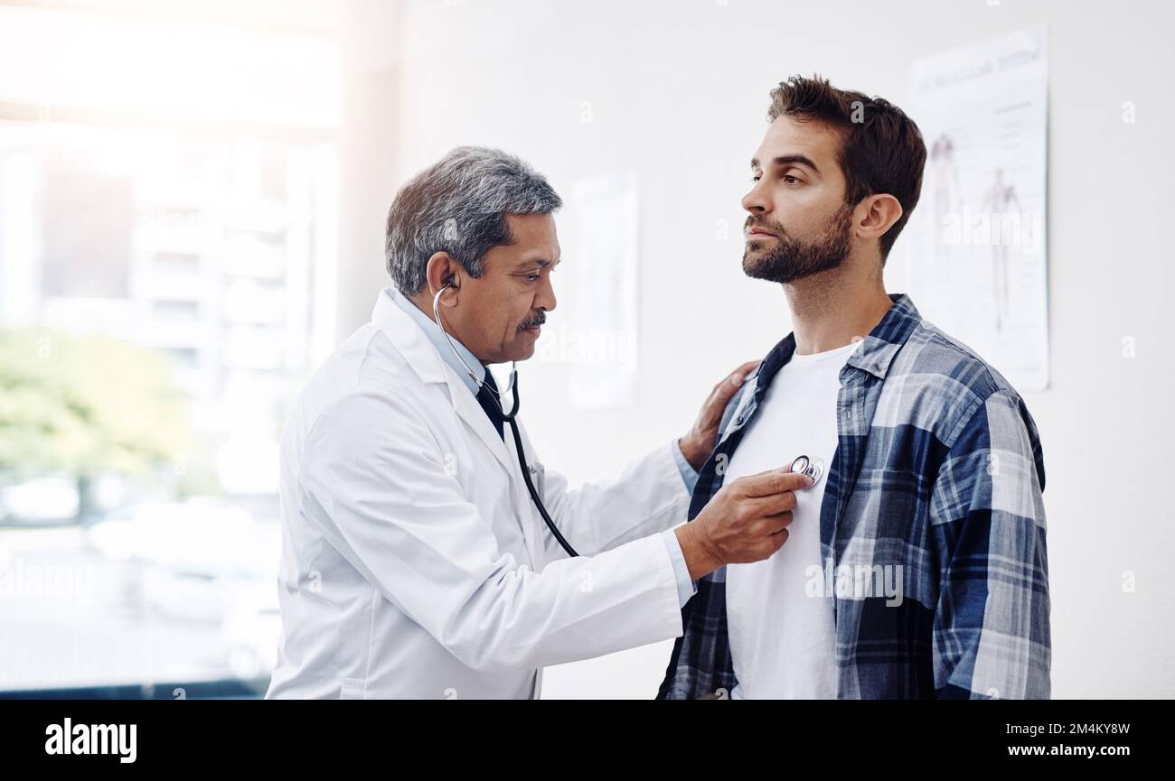 Prenez une profonde respiration... un homme mature médecin et patient ayant une discussion dans le bureau des médecins pendant un examen. Banque D'Images