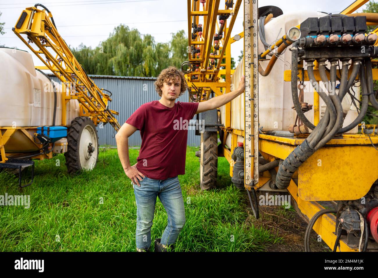 Ouvrier agricole debout sur l'herbe parmi deux batcheurs Banque D'Images