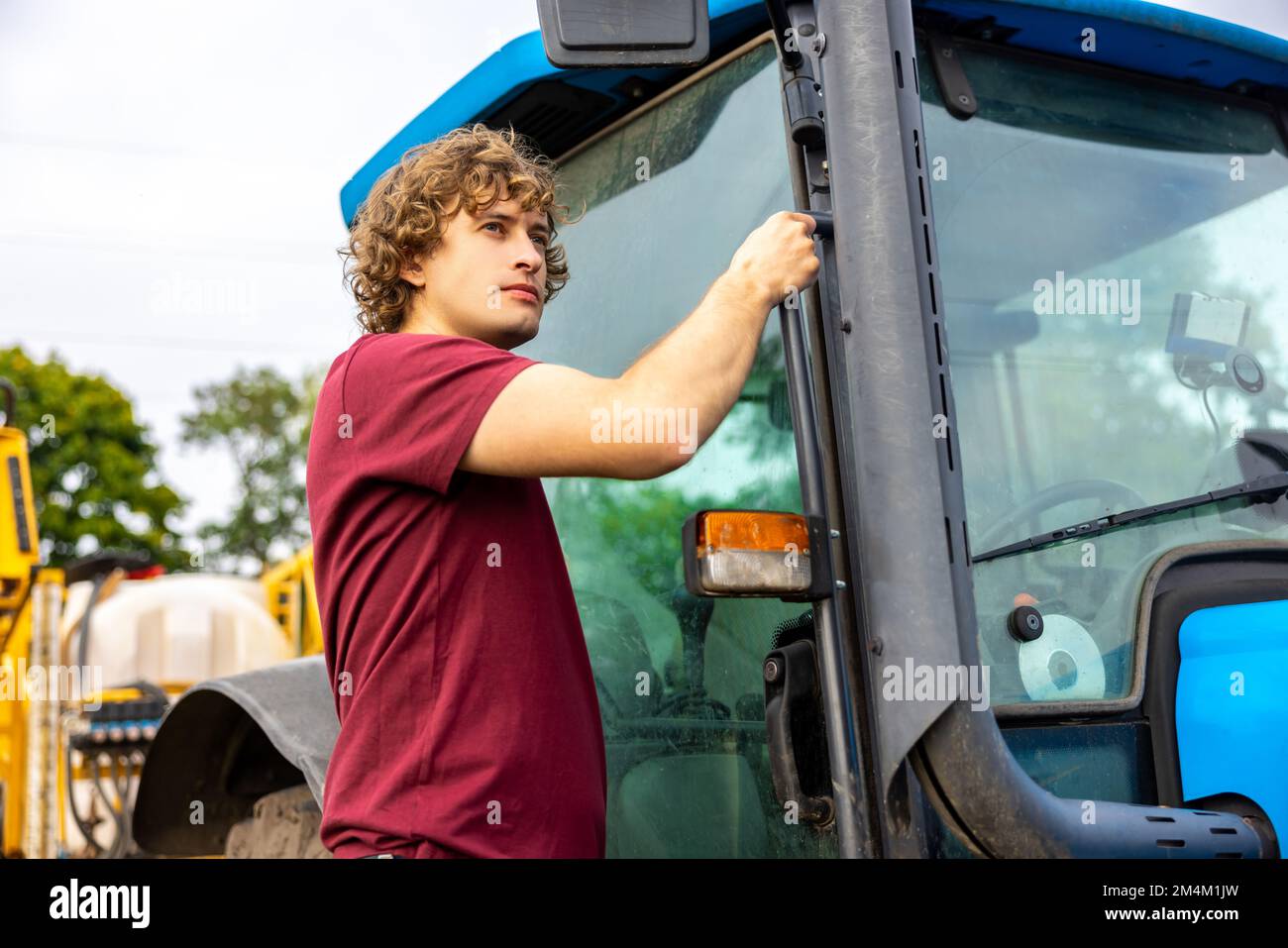 Jeune conducteur de tracteur caucasien focalisé sur quelque chose Banque D'Images