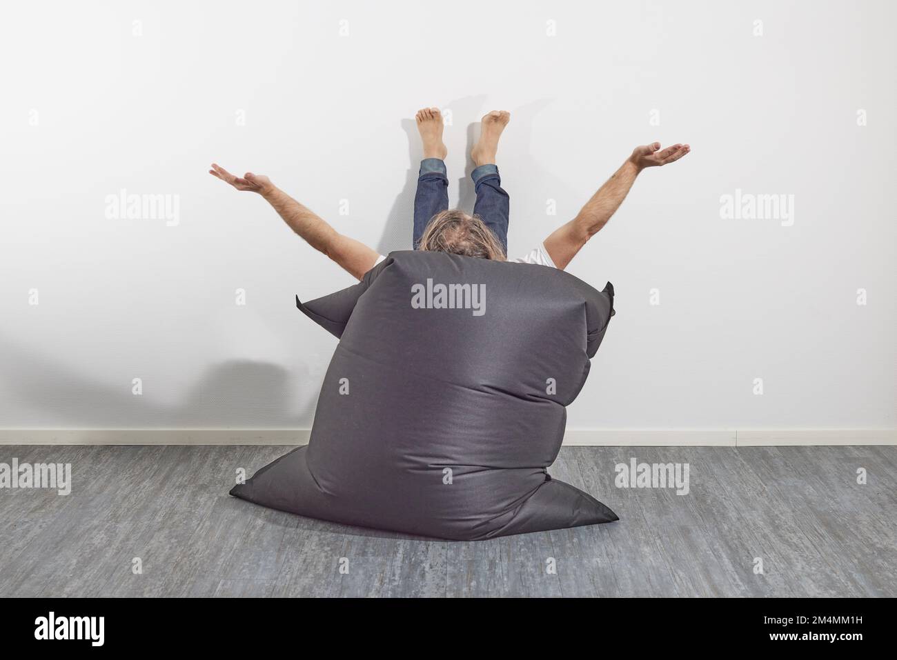 Homme se reposant sur un sac de beanbag avec la nourriture sur le mur Banque D'Images