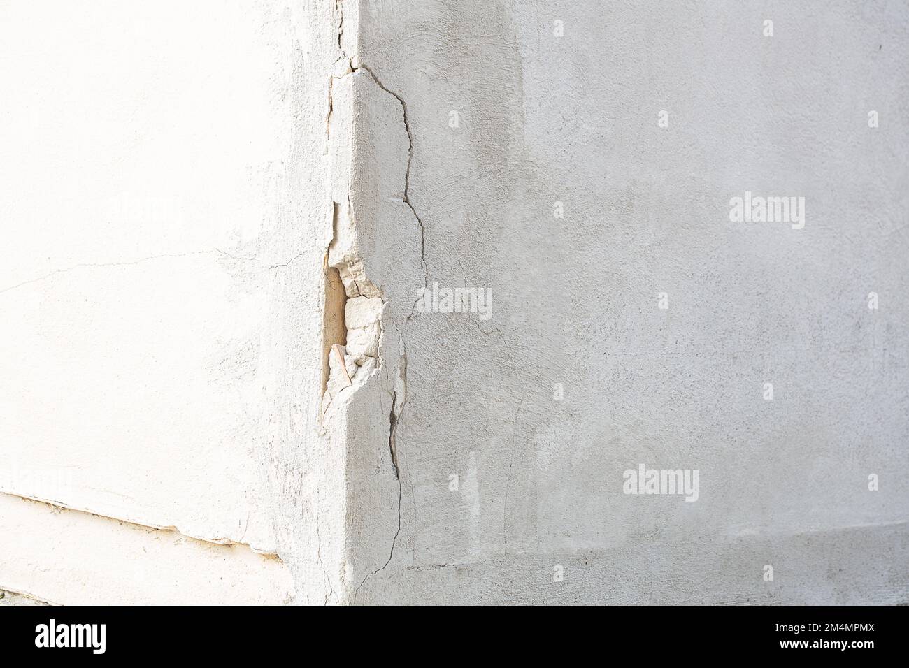 Dommages dans le coin d'une lande blanche externe. Des fissures et une partie du plâtre est tombée. Concept d'utilisation de matériaux pauvres et de décomposition Banque D'Images