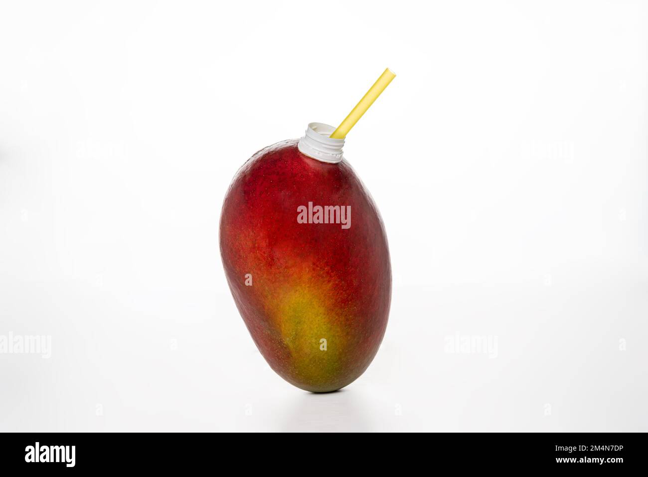 Mangue, fruit sur fond blanc, avec une paille dans le bec pour pouvoir boire comme une bouteille de jus. Banque D'Images